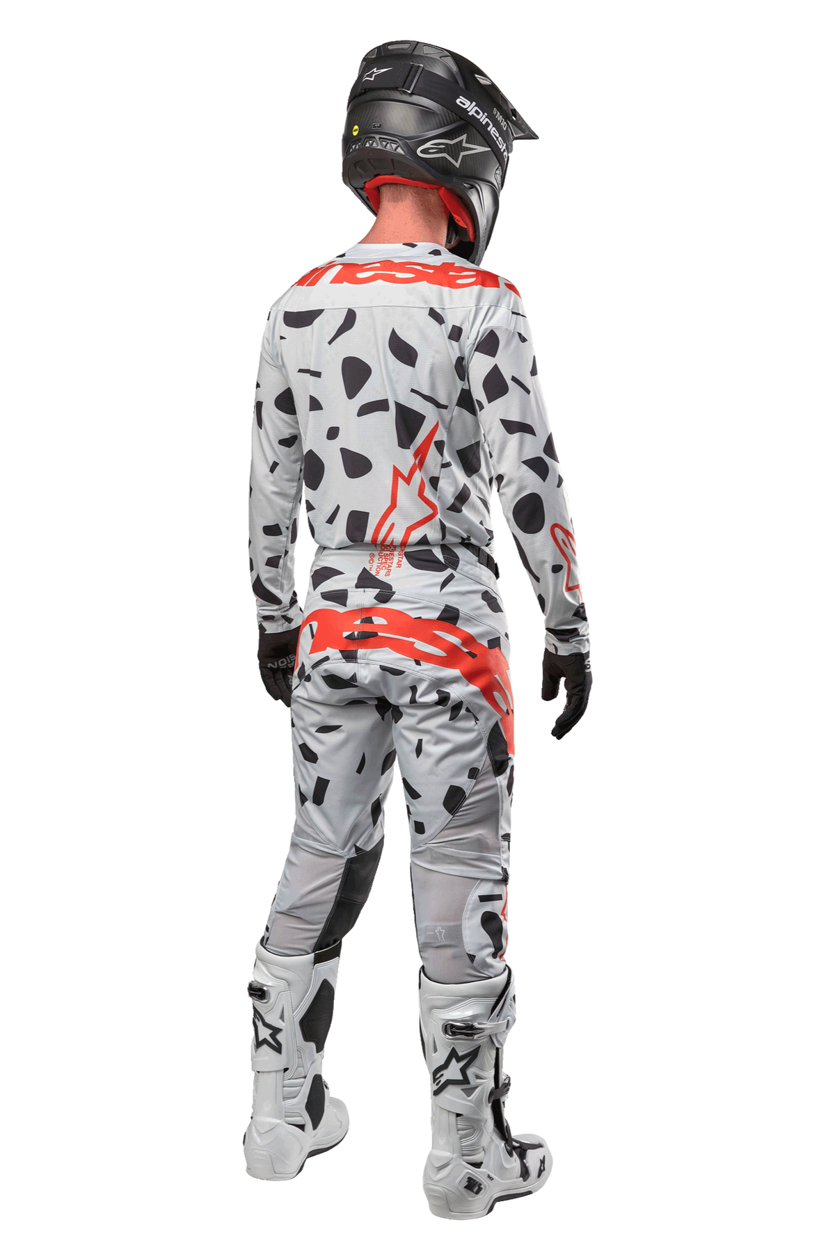 Motocrossförare sedd bakifrån iklädd Alpinestars 2024 Techstar Rantera-byxor, Haze Gray Camo med svarta fläckar och röda logotyper, matchande tröja, svart hjälm och vita stövlar, komplett outfit för terrängkörning