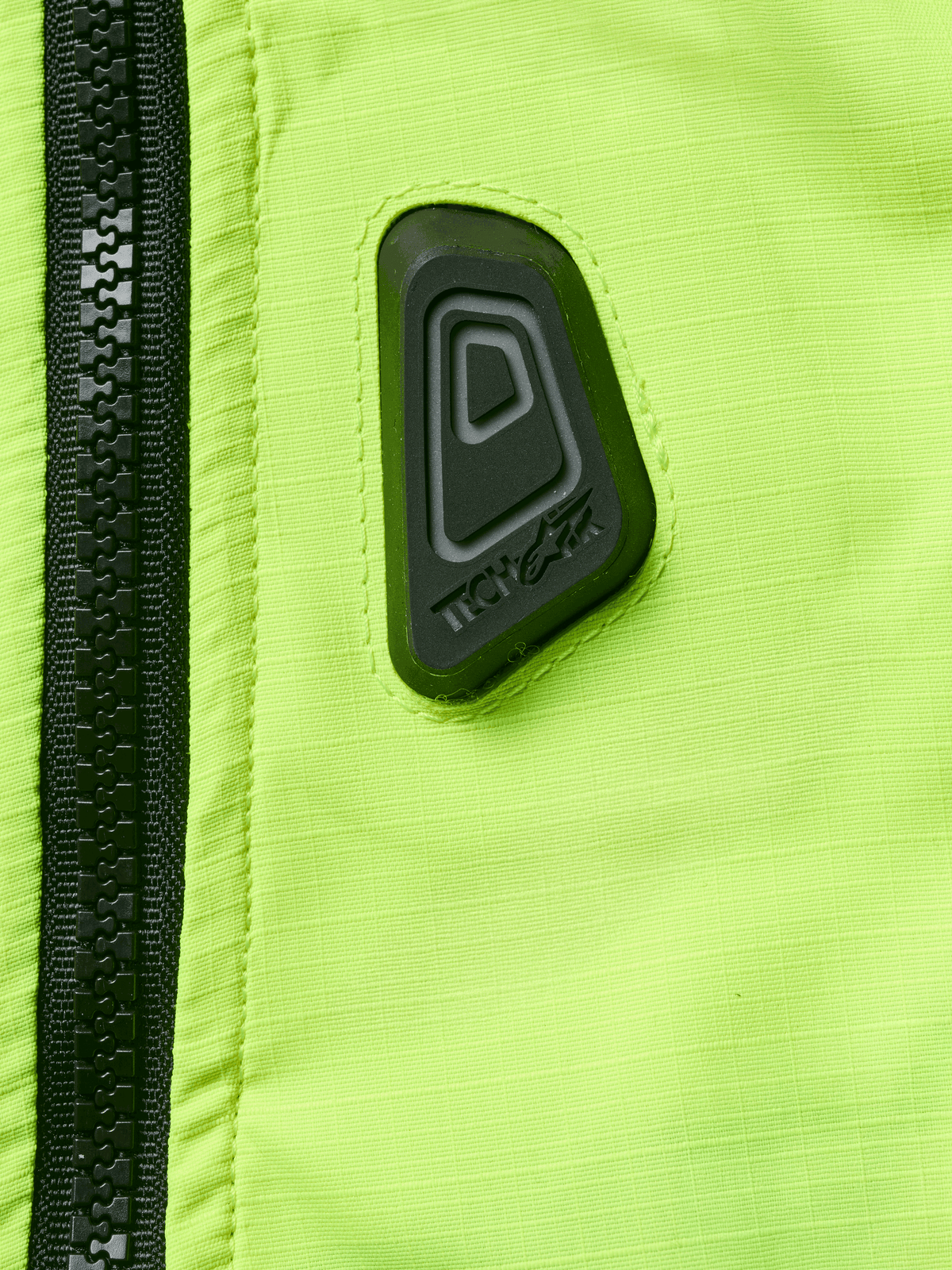 Alpinestars Tech-Air® 3 V2-system, airbagväst för motorcykel, närbild på vattenresistent tyg i Yellow Fluo med svart dragkedja och en svart gummerad Tech-Air-logotyp, säkerhetsutrustning med hög synlighet