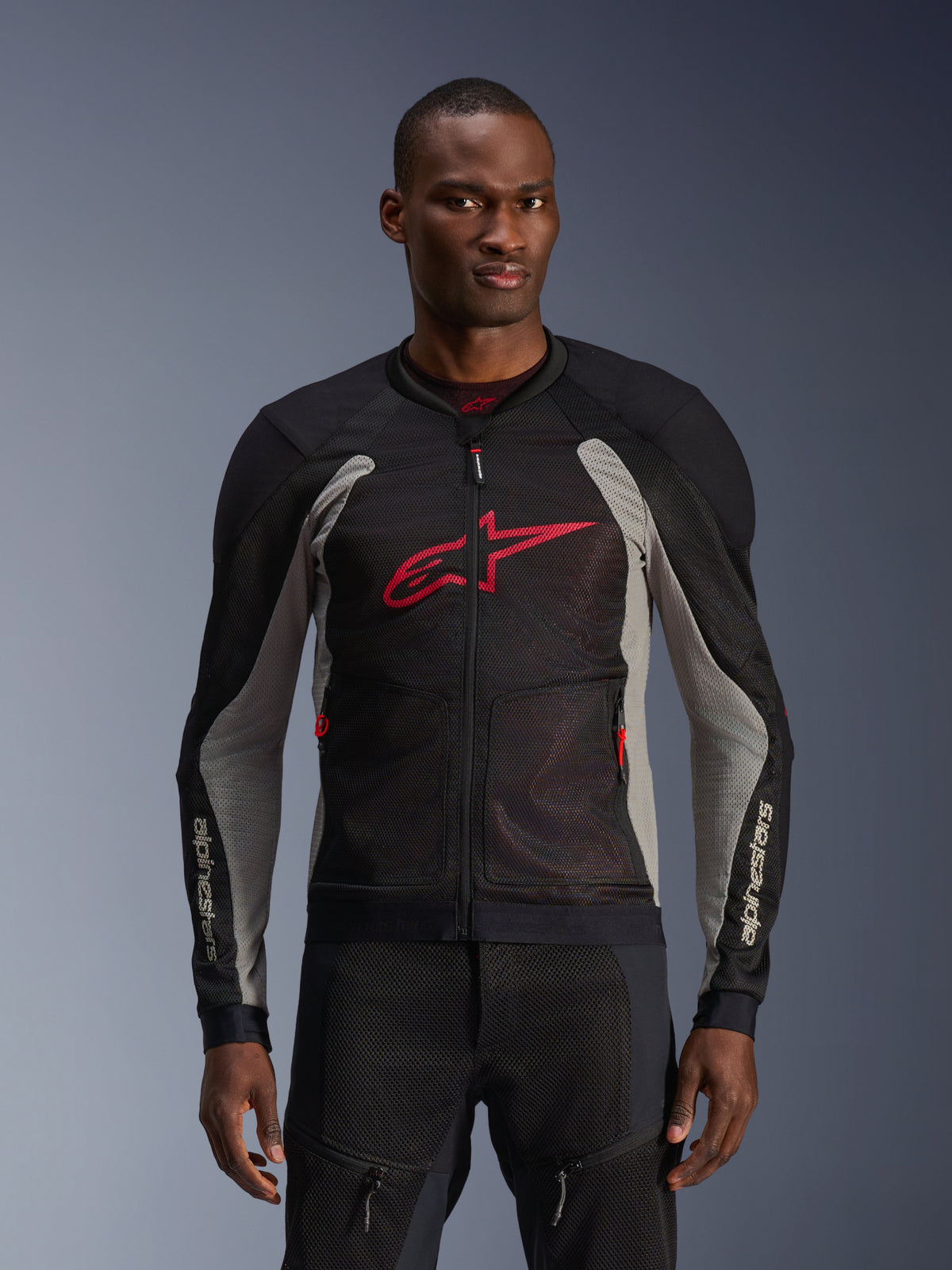 Alpinestars Troop-Air jacka, motorcykeljacka i mesh, svart och askgrå med klarröda detaljer, bärs av en modell, ventilerande 2D-tech meshpaneler, stor röd Astars-logotyp på bröstet, teknisk sportig design för stadskörning