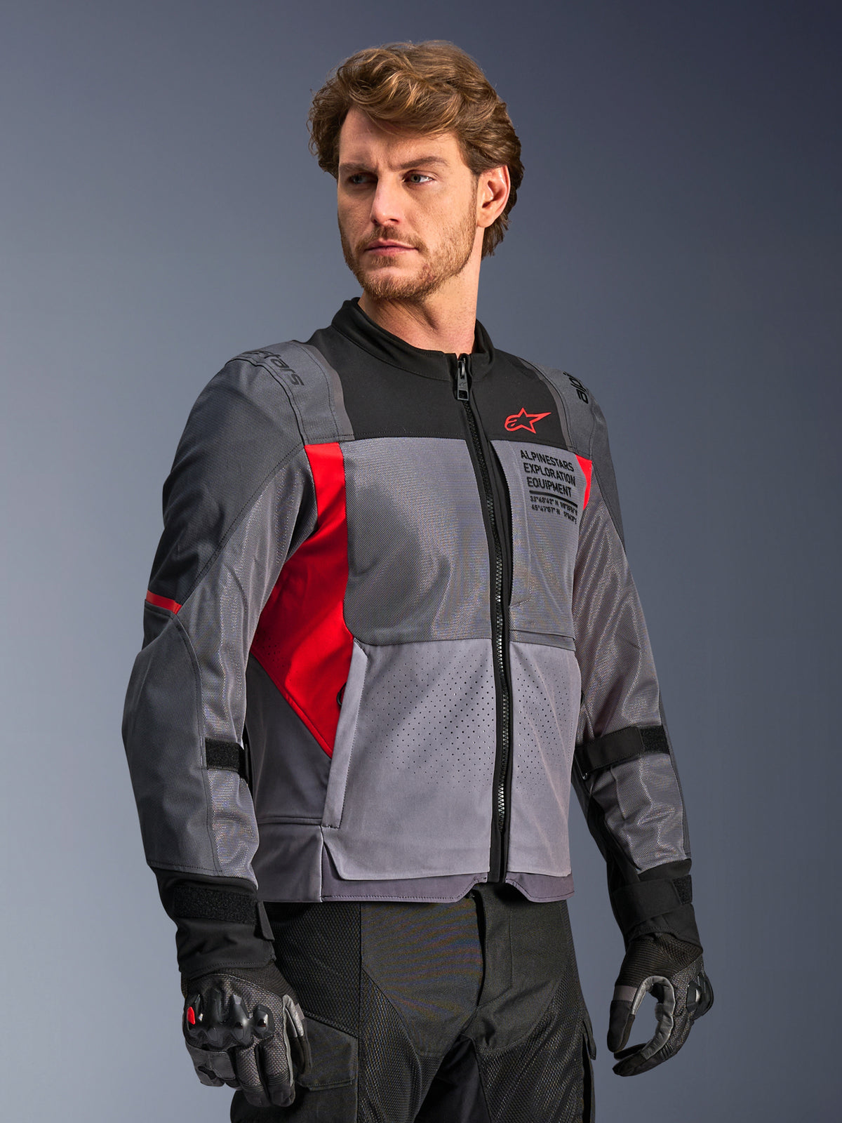 Alpinestars ST-2 Air jacka, grå och röd touring-motorcykeljacka i mesh med laserperforeringar, bärs av en manlig modell.