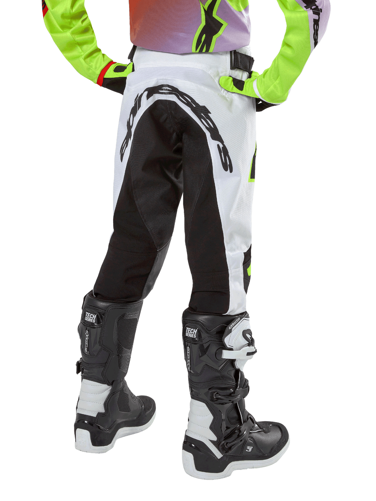 Alpinestars Youth 2024 Racer Lucent byxor, motocrossbyxor, vita och svarta med neonfärgade detaljer, baksida som visar stor bakre stretchpanel och Alpinestars-logotyp, bärs tillsammans med svarta och vita Alpinestars Tech Series-stövlar.