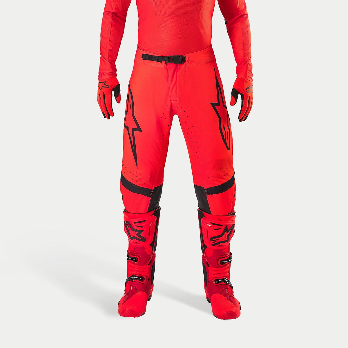 Alpinestars Supertech Ember LE byxor, motocrossbyxor, Red Fluo och klarröda med svarta detaljer, med framträdande svarta stjärnlogotyper på låren, svart midjespänne och knäpaneler, bärs med matchande röda stövlar och handskar för en koordinerad racingoutfit.