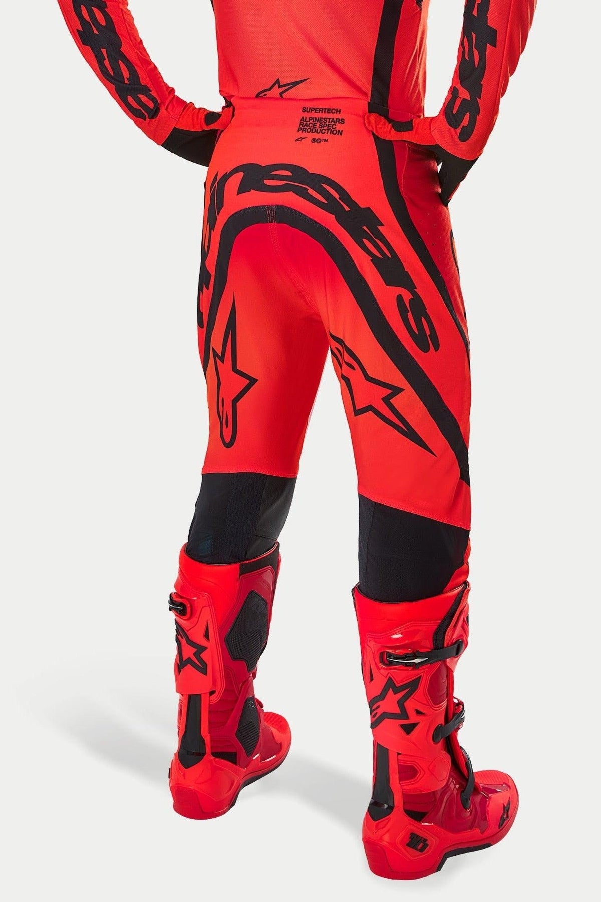 Alpinestars Supertech Ember LE-byxor, motocrossbyxor, röd fluo, ljusröd och svart, baksida med stor svart logotyp på sätet och stjärnlogotyper, bärs med matchande röda motocross-stövlar, professionell racingutrustning för terrängprestanda