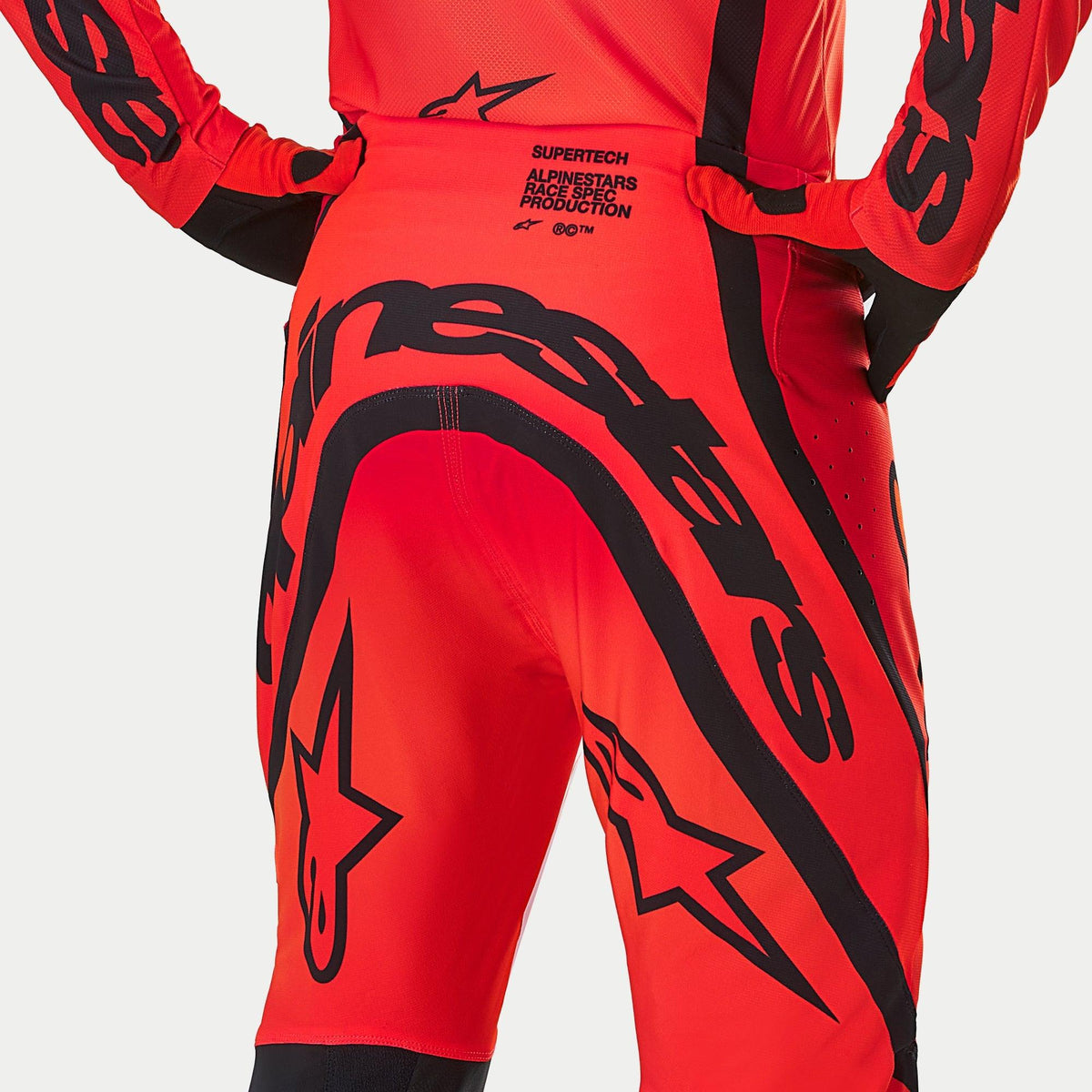 Alpinestars Supertech Ember LE-byxor, motocrossbyxor, Red Fluo och Bright Red med svart grafik, vy bakifrån som framhäver tydlig branding och texten 'Race Spec Production' på ländryggen, prestandakonstruerad design för terrängkörning