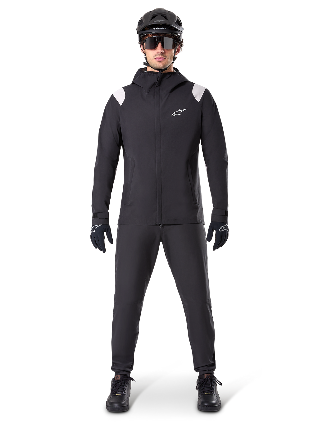Alpinestars A-Dura regnjacka, regnjacka för mountainbike, svart med vita axeldetaljer och vit logotyp på bröstet, bärs med svarta byxor, svart hjälm, solglasögon och handskar, matchande mountainbike-utrustning för vått väder