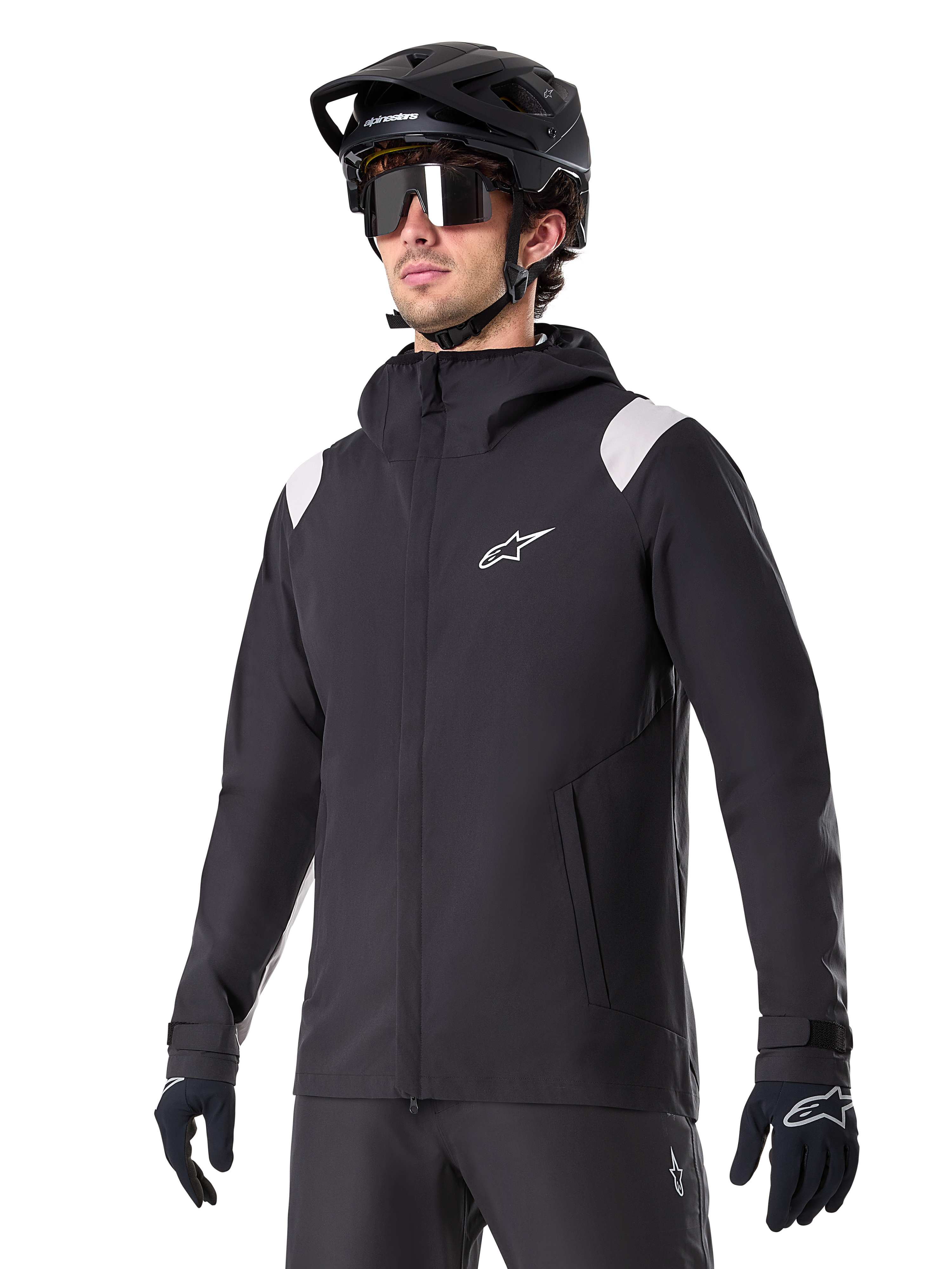 Alpinestars A-Dura regnjacka, regnjacka för mountainbike, svart med ljusgrå axeldetaljer, bärs av en cyklist med svart MTB-hjälm och solglasögon, vit logotyp på bröstet, vattentät konstruktion, matchad med svarta byxor och handskar för terrängcykling