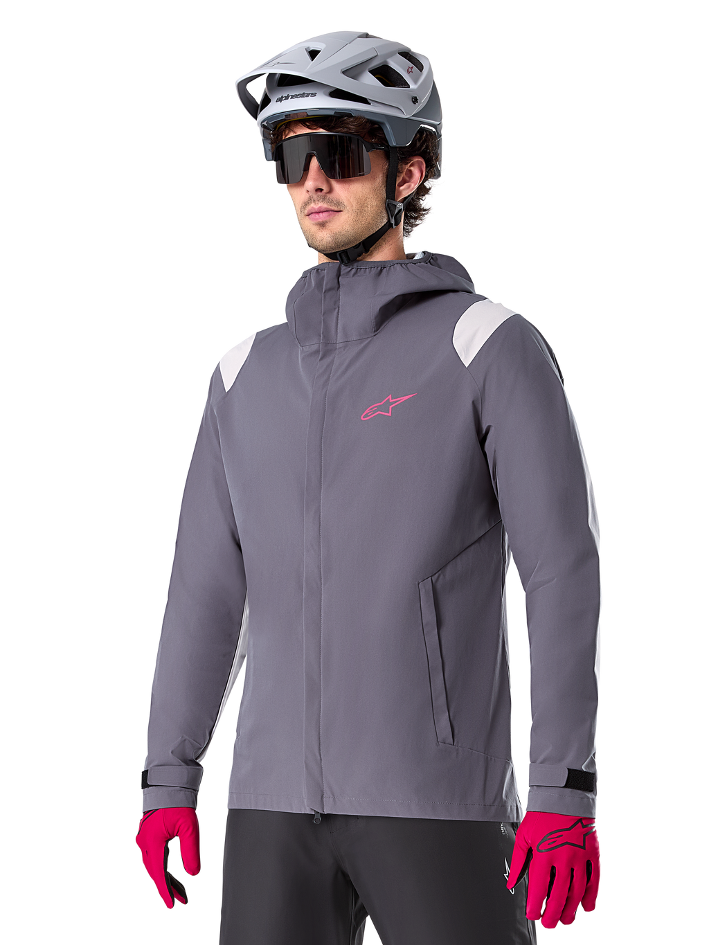 Alpinestars A-Dura regnjacka, regnjacka för mountainbike, mörkgrå med rosa logotyp och vita axeldetaljer, design med huva och framfickor, bärs med rosa handskar och en ljusgrå cykelhjälm