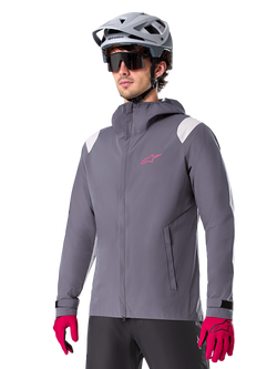 Alpinestars A-Dura Rain Jacket, Mountain Bike Rain Jacket, Dark Titanium Gray with pink logo and white shoulder accents, hooded design with front pockets, worn with pink gloves and a light gray cycling helmet