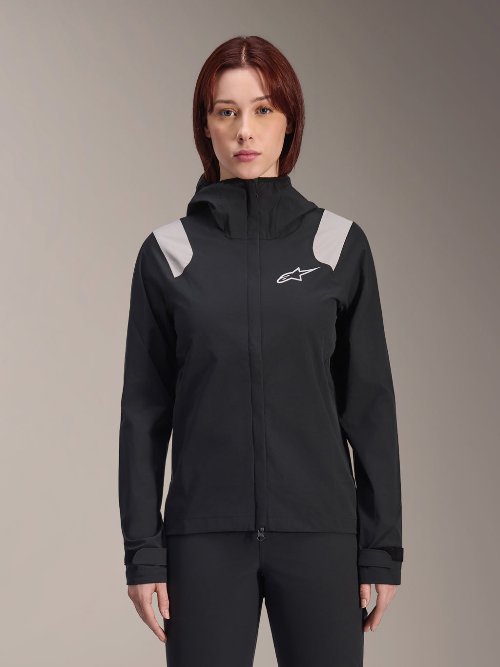 Alpinestars Stella A-Dura regnjacka, regnjacka för damcykling, svart med ljusgrå axelpaneler, tekniskt skalplagg med huva och vit logotyp på bröstet, justerbara manschetter med kardborre, professionell utrustning för MTB och cykling i vått väder