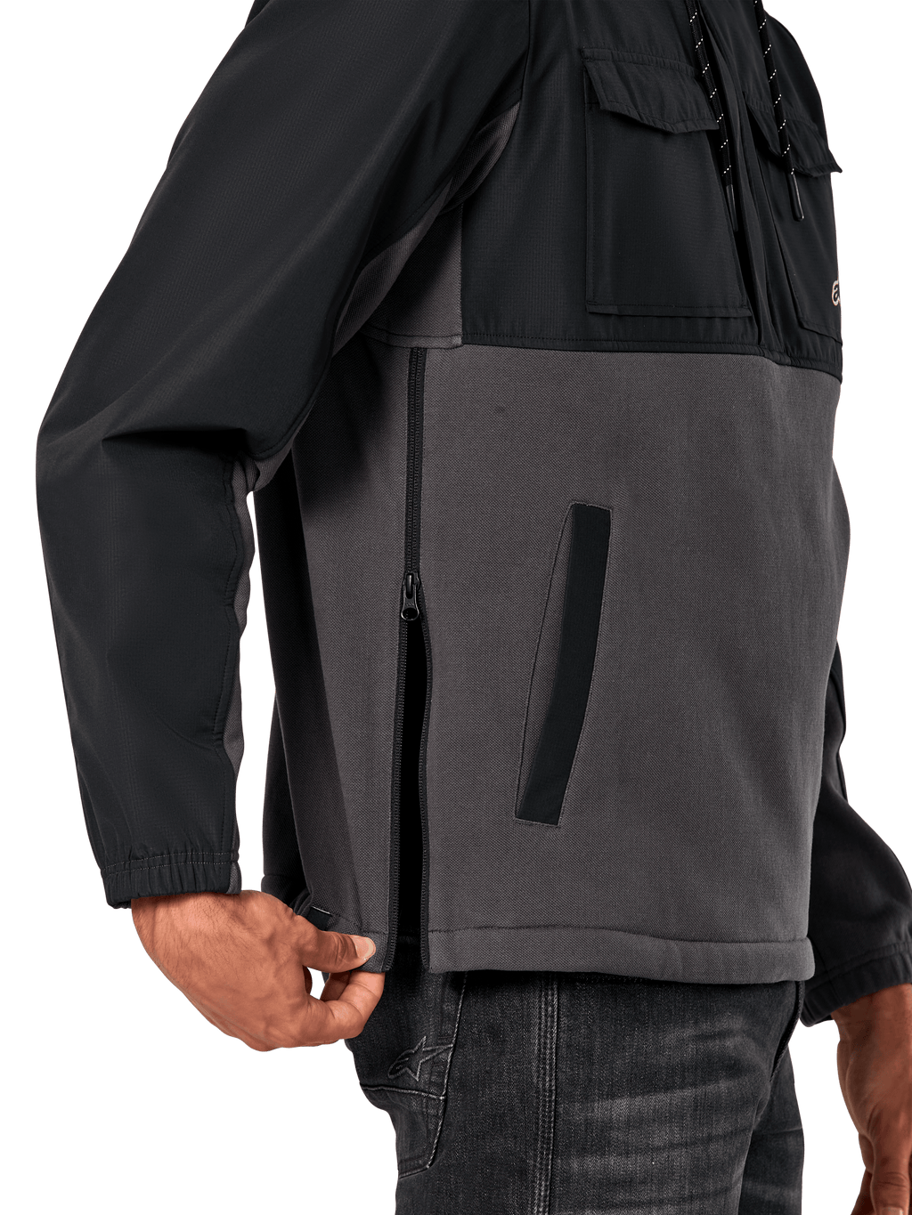 Alpinestars Juncture Hybrid-jacka i Black Gunmetal, sidodetalj som visar sidodragkedjan och den nedre kantfickan, design i mixade material med grå canvasfleece och svarta ripstop-överdrag, avslappnad motorsportinspirerad streetwear