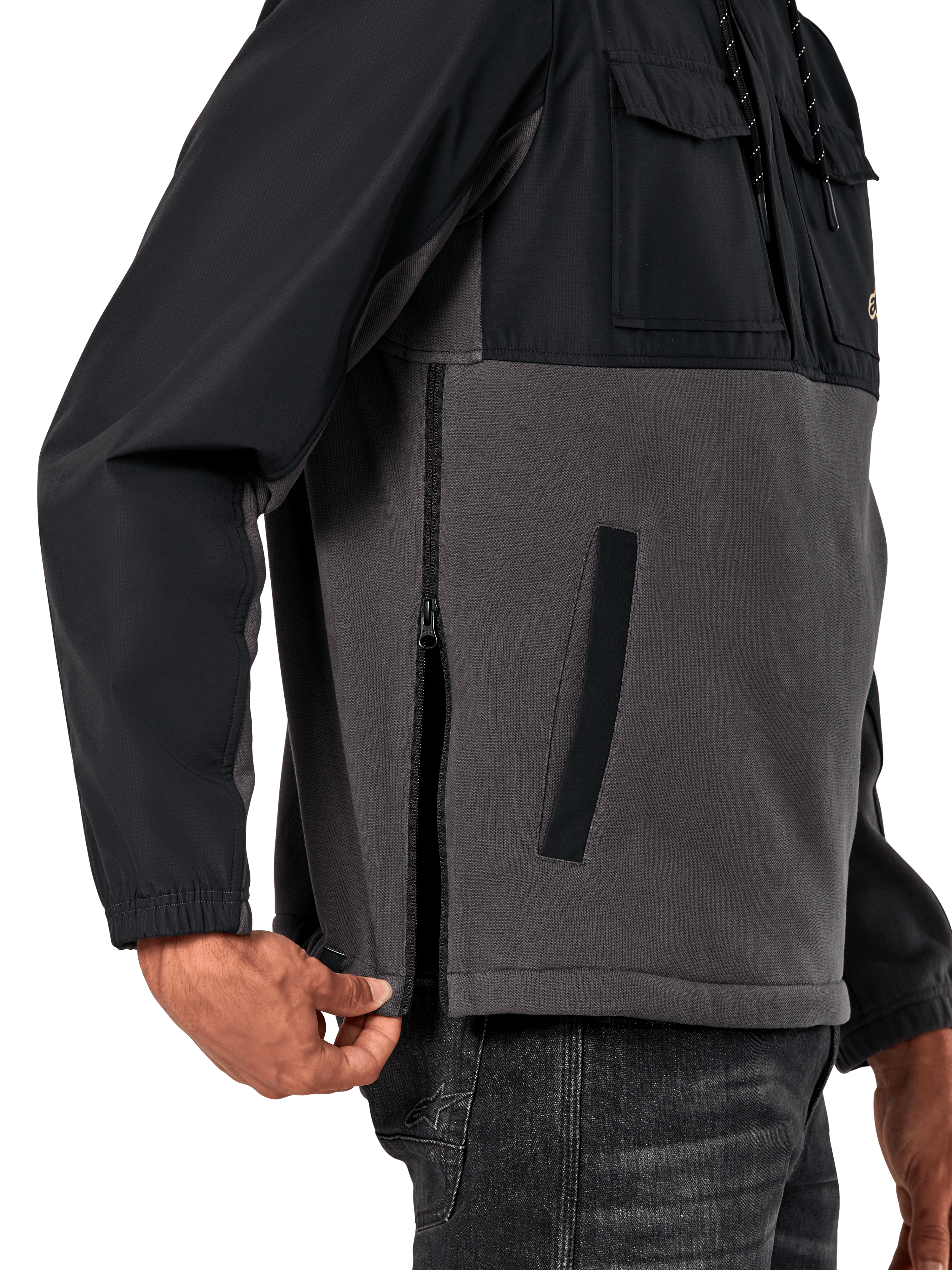 Alpinestars Juncture Hybrid-jacka i Black Gunmetal, sidodetalj som visar sidodragkedjan och den nedre kantfickan, design i mixade material med grå canvasfleece och svarta ripstop-överdrag, avslappnad motorsportinspirerad streetwear