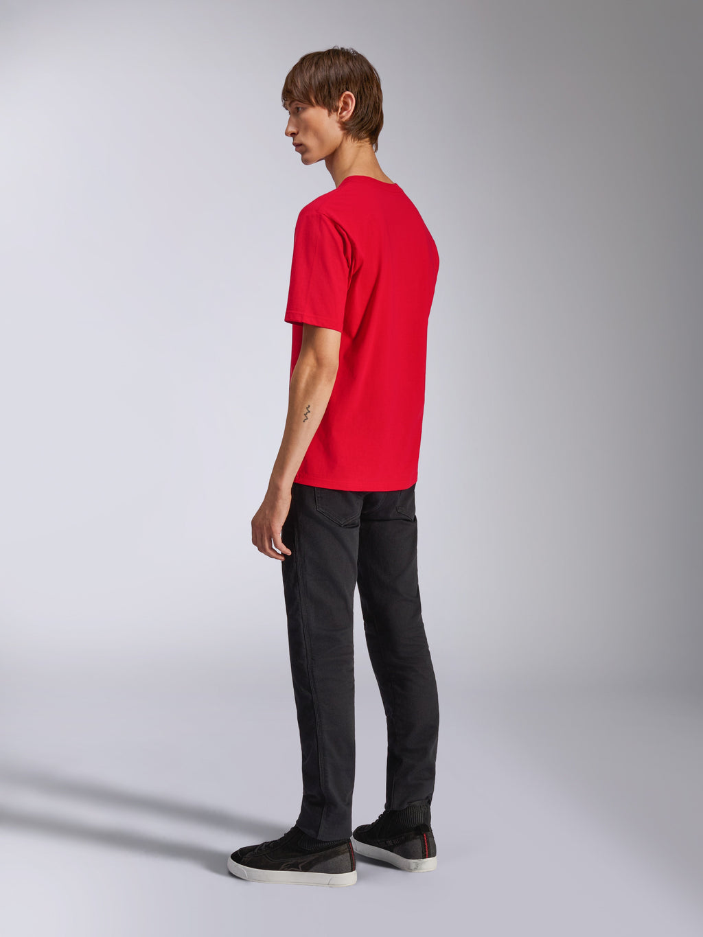 Alpinestars Ageless Shadow CSF Tee, kortärmad t-shirt, röd, vy bakifrån på modell, bärs med svarta byxor och sneakers, avslappnad motorsport-inspirerad streetwear