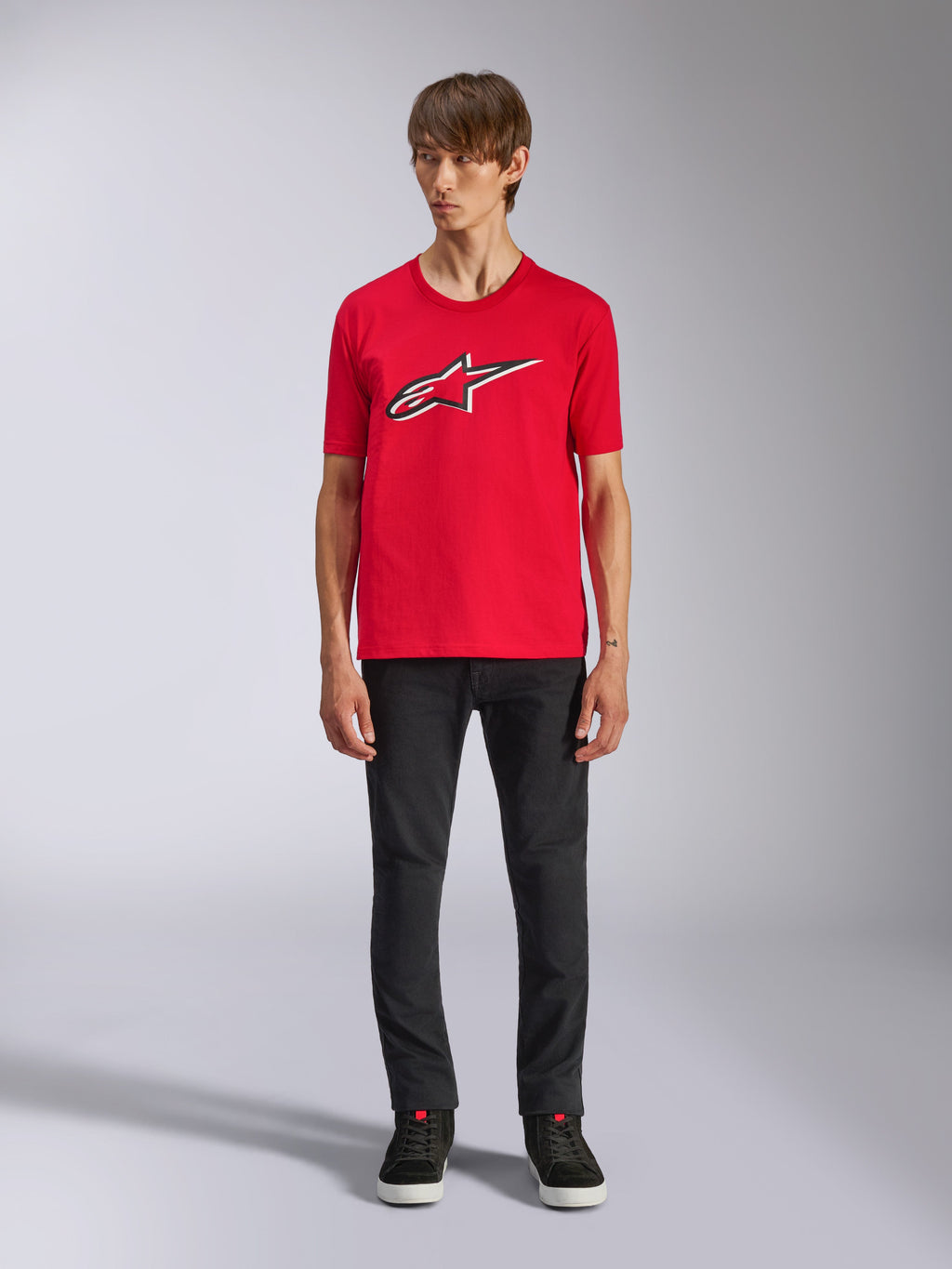 Alpinestars Ageless Shadow CSF T-shirt, kortärmad t-shirt, röd, Ageless-logotyp framtill med vita och svarta konturer, bärs av en modell med svarta byxor och sneakers, casual motorsport-streetwear