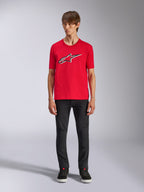 Alpinestars Ageless Shadow CSF T-shirt, kortärmad t-shirt, röd, Ageless-logotyp framtill med vita och svarta konturer, bärs av en modell med svarta byxor och sneakers, casual motorsport-streetwear