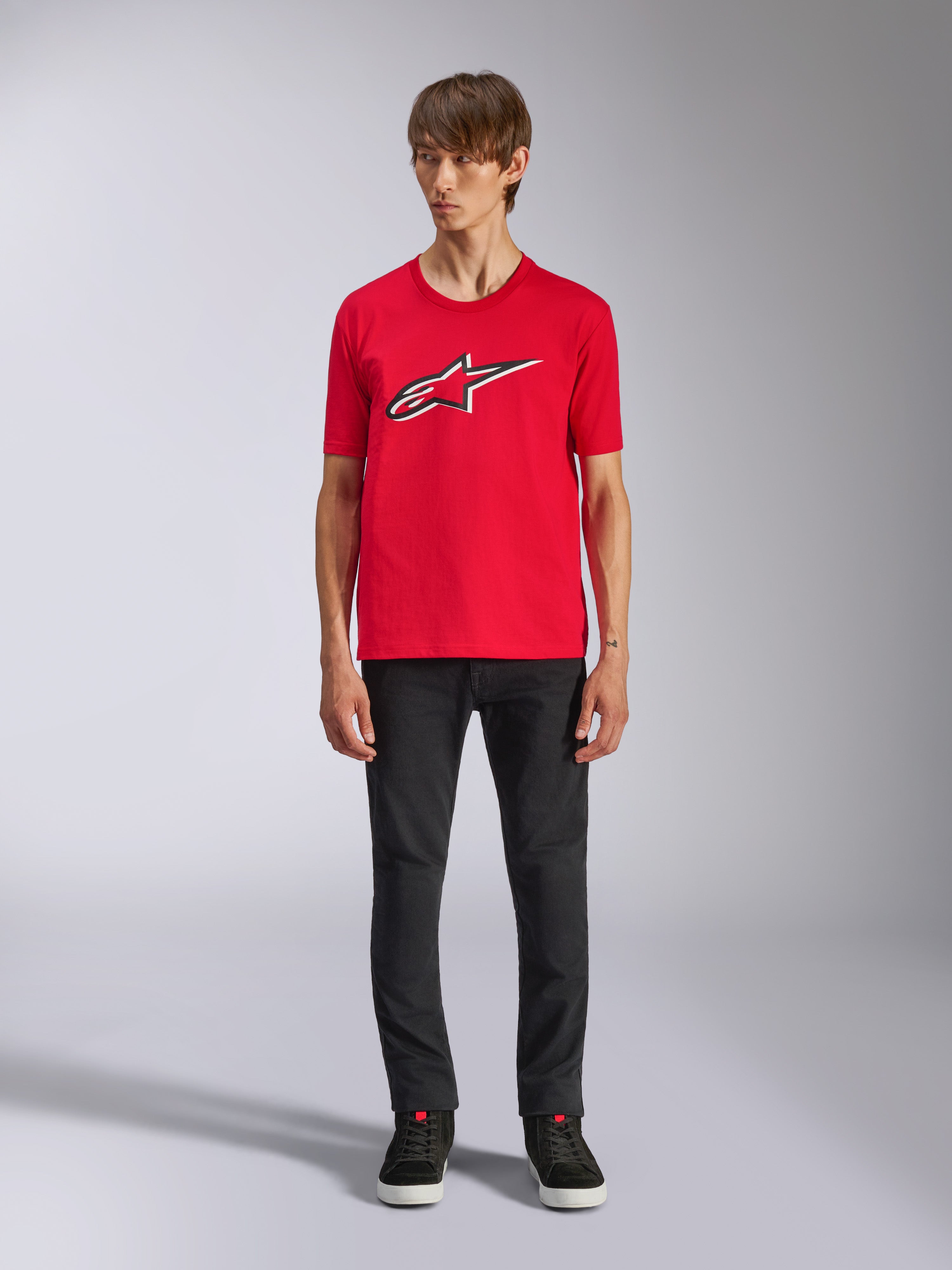 Alpinestars Ageless Shadow CSF T-shirt, kortärmad t-shirt, röd, Ageless-logotyp framtill med vita och svarta konturer, bärs av en modell med svarta byxor och sneakers, casual motorsport-streetwear