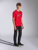 Alpinestars Ageless Shadow CSF Tee, röd kortärmad t-shirt, med en stor Ageless-logotyp på bröstet, bärs av en modell med svarta byxor och sneakers, avslappnad motorsport-streetwear