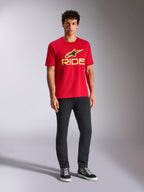 Alpinestars Ride 4.0 CSF Tee, kortärmad t-shirt, röd med varselgul Alpinestars-stjärna och Ride-logotyp, bärs av modell med svarta byxor och sneakers, avslappnade motorsportkläder