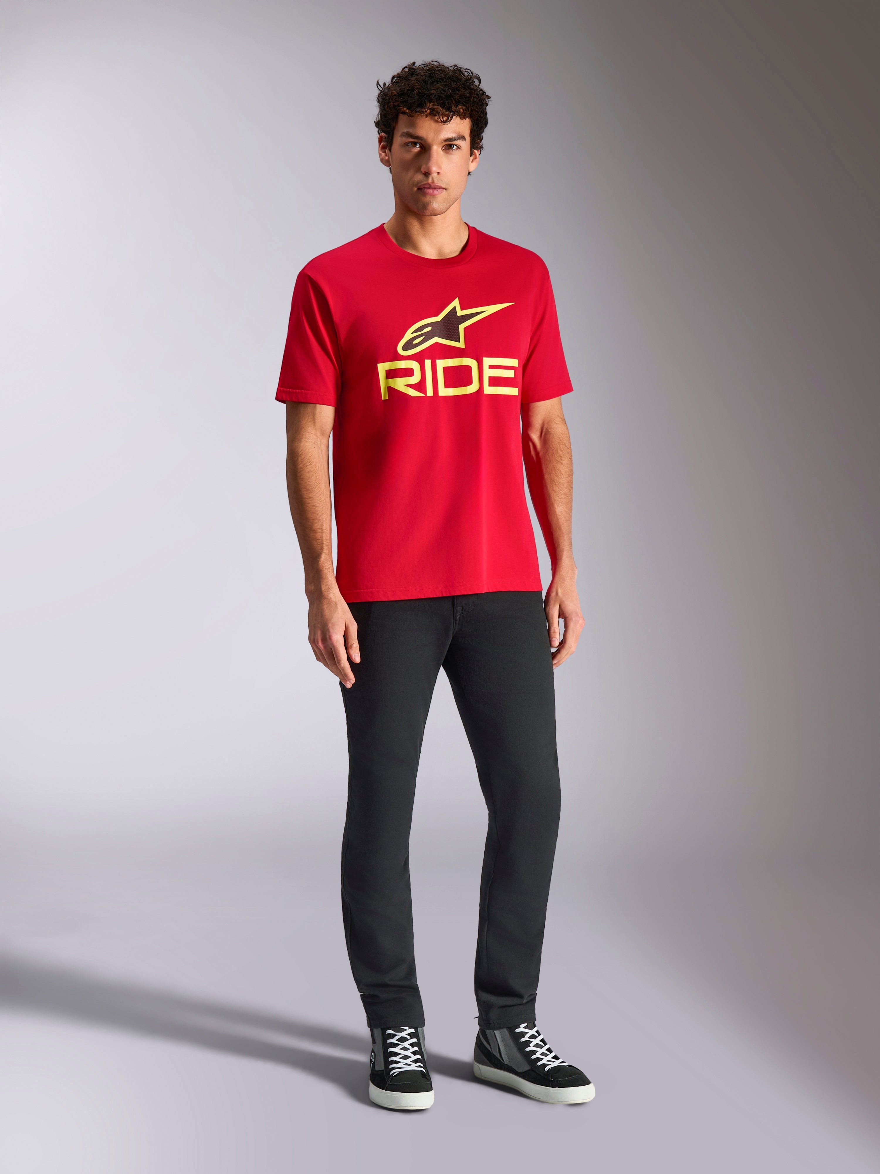 Alpinestars Ride 4.0 CSF Tee, kortärmad t-shirt, röd med varselgul Alpinestars-stjärna och Ride-logotyp, bärs av modell med svarta byxor och sneakers, avslappnade motorsportkläder