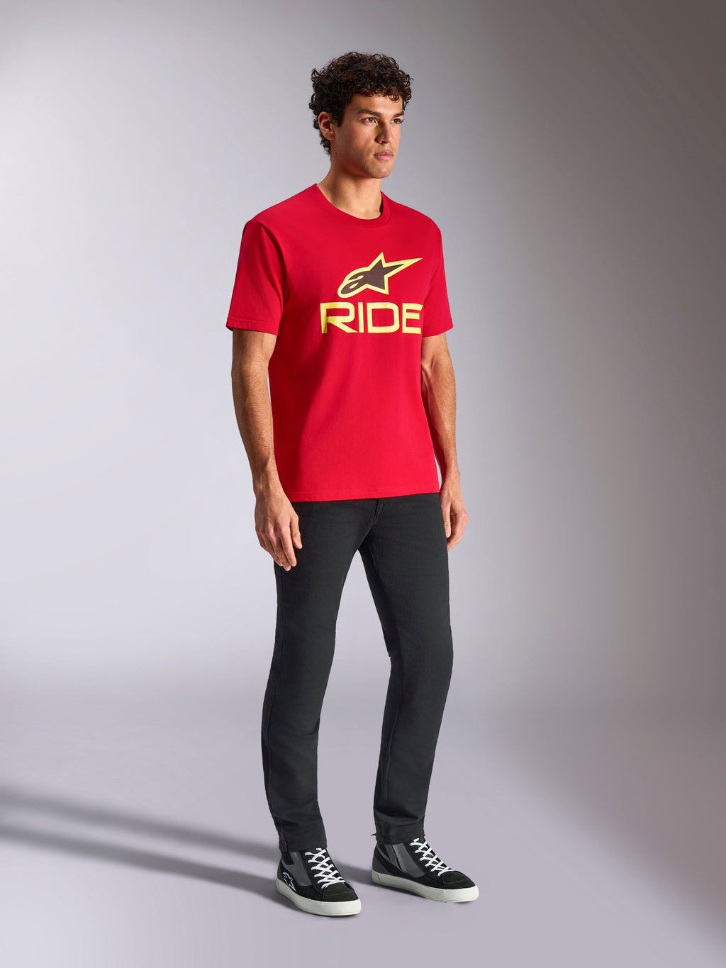Alpinestars Ride 4.0 CSF Tee, kortärmad T-shirt, röd, gul och svart logotyp på framsidan, bärs med svarta byxor och sneakers, avslappnad motorsport-streetwear