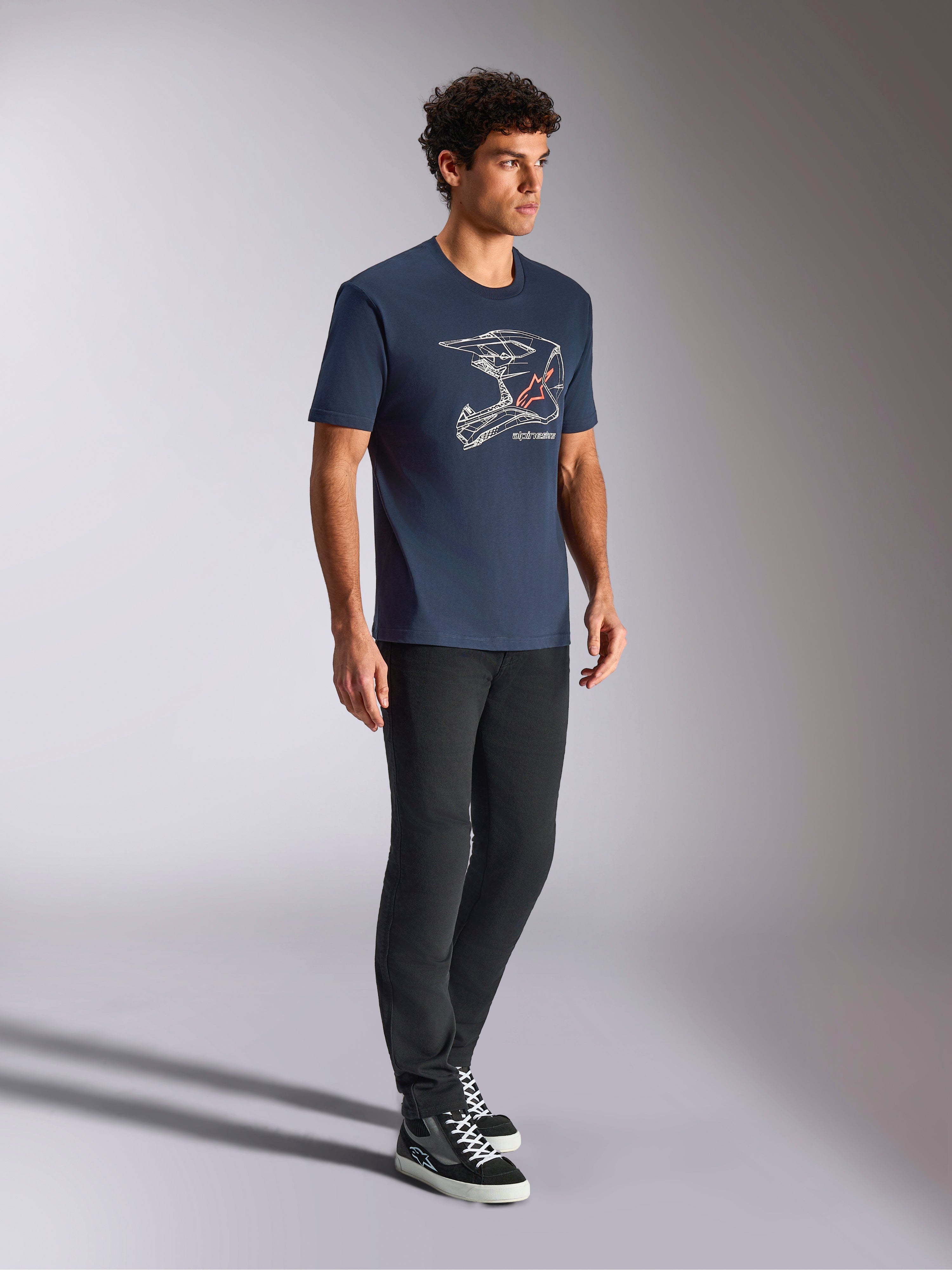 Alpinestars MX Helmet CSF Tee, kortärmad t-shirt, marinblå, vit linjekonst av en motocrosshjälm med röd stjärnlogotyp, avslappnad motorsportinspirerad streetwear bärs med svarta byxor och höga sneakers
