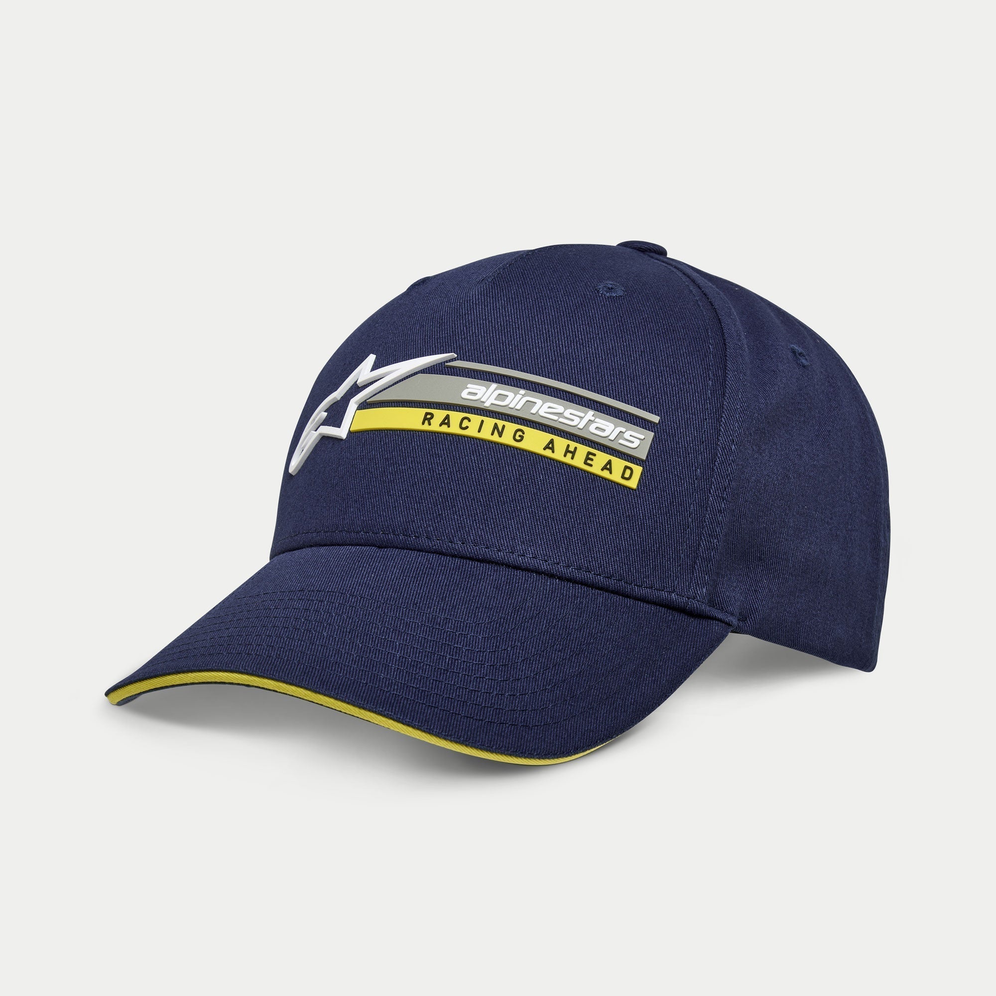 Alpinestars Par Hat, mörkblå snapback-keps, böjd skärm med gul sandwich-kant, 3D-broderad logotyp med 'Racing Ahead'-grafik, vardaglig motorsportinspirerad huvudbonad