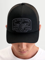 Alpinestars Heritage Patch keps, svart och grå trucker-keps med böjd skärm, strukturerad krona, poly mesh-baksida och stor broderad logopatch, bärs av en modell