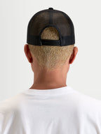 Alpinestars Heritage Patch keps, svart trucker-keps, vy bakifrån som visar justerbar snapback-knäppning och poly mesh-konstruktion, bärs av en modell