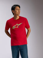 Alpinestars Ageless Shadow CSF Tee, kortärmad t-shirt, röd, gul och blå skugglogotyp på bröstet, avslappnad motorsport-streetwear som bärs med blå jeans