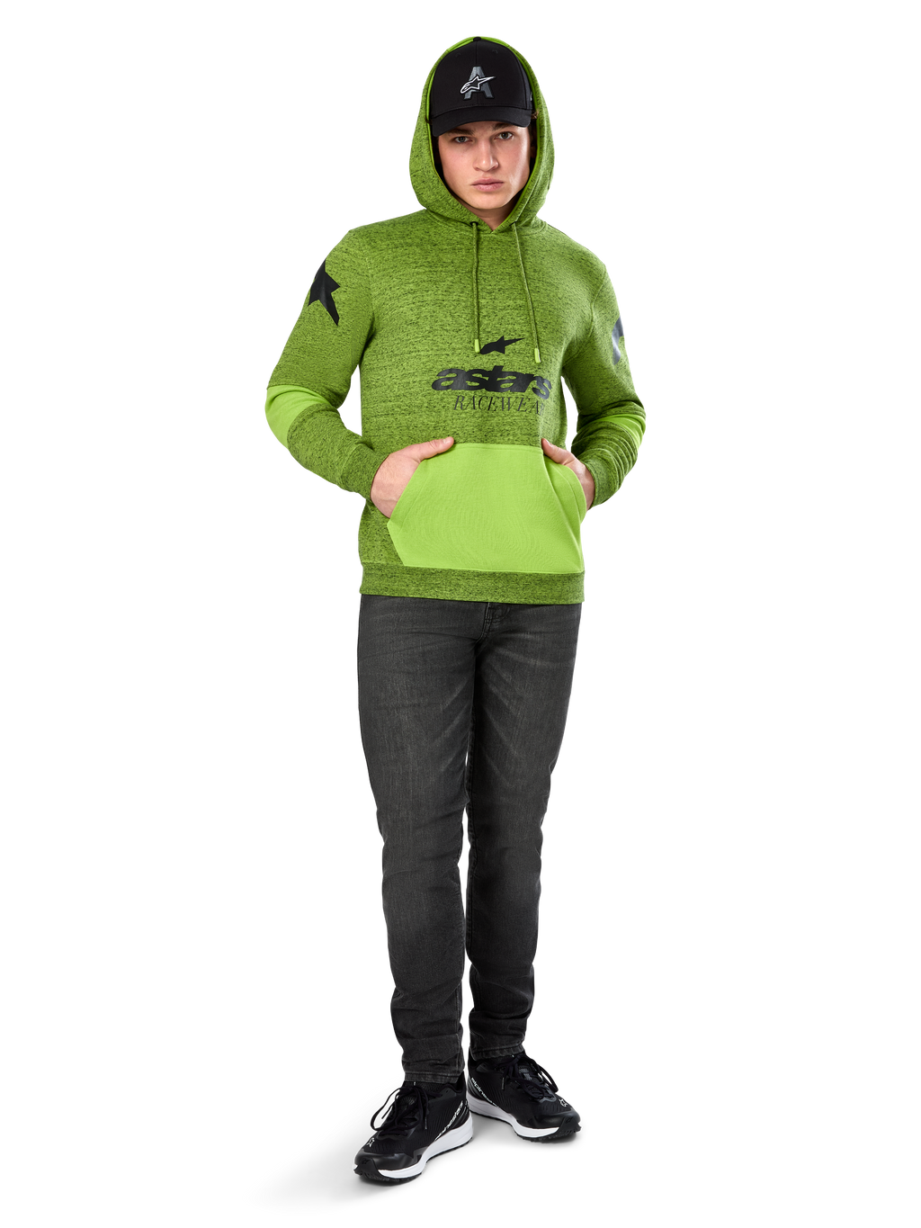 Alpinestars Perpetuate Hoodie, limegrön melerad fleece i pullovermodell med kontrasterande klargrön känguruficka och ärmpaneler, svart 'astars'-grafik framtill, stylad med svart keps och mörka jeans, avslappnad motorsport-inspirerad streetwear
