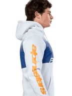Alpinestars Specter Hoodie, casual streetwear, vit med blått tonat gradienttryck, stor orange Alpinestars-ordlogotyp på ärmen, sidoprofil av man som bär huvtröja i pullover-modell