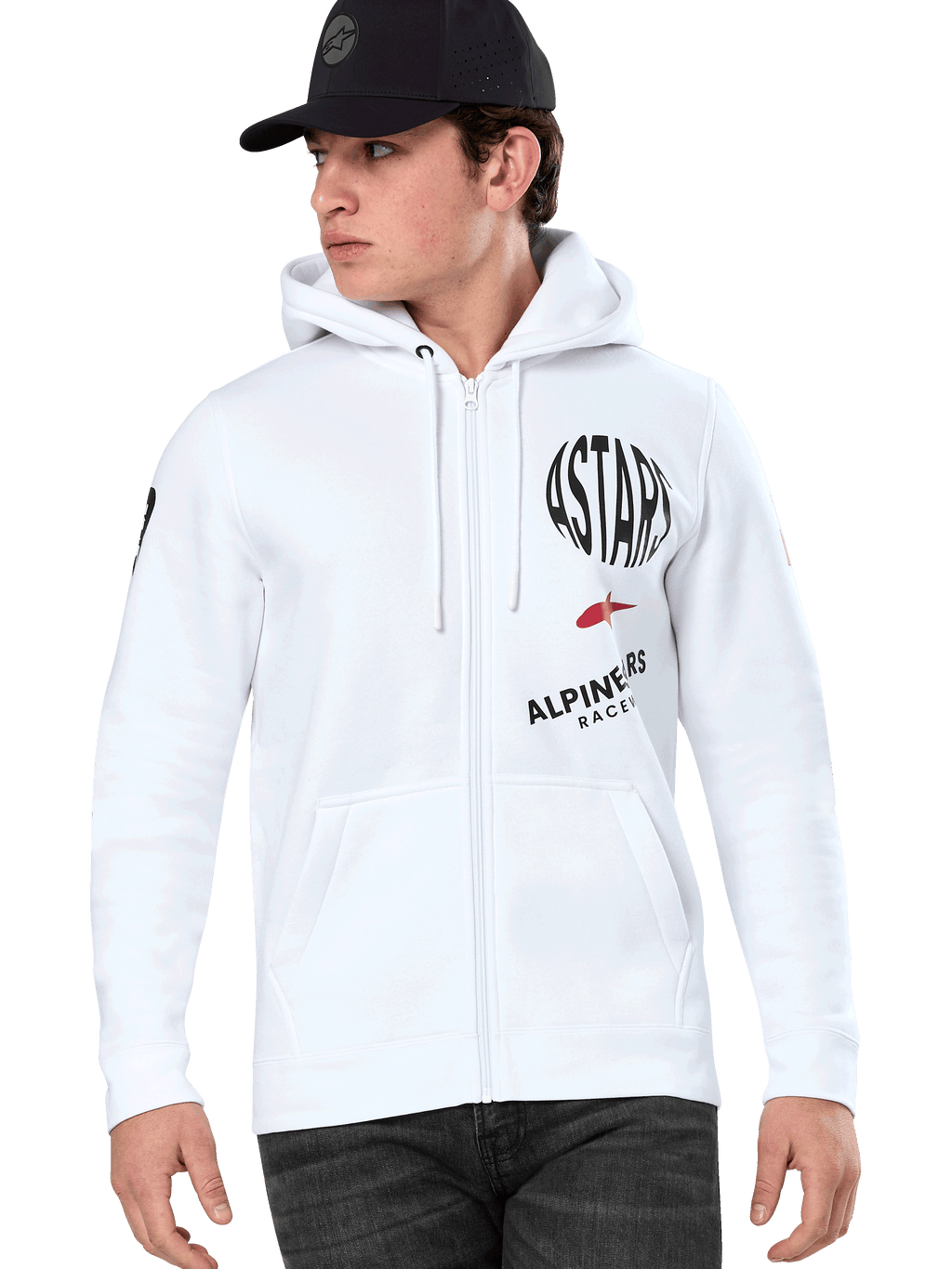 Alpinestars Variegate Hoodie, vit zip-hoodie med svart och röd ASTARS-racinggrafik, bärs av en modell med svart keps och mörka jeans, avslappnad motorsport-streetwear med känguruficka och huva med dragsnöre