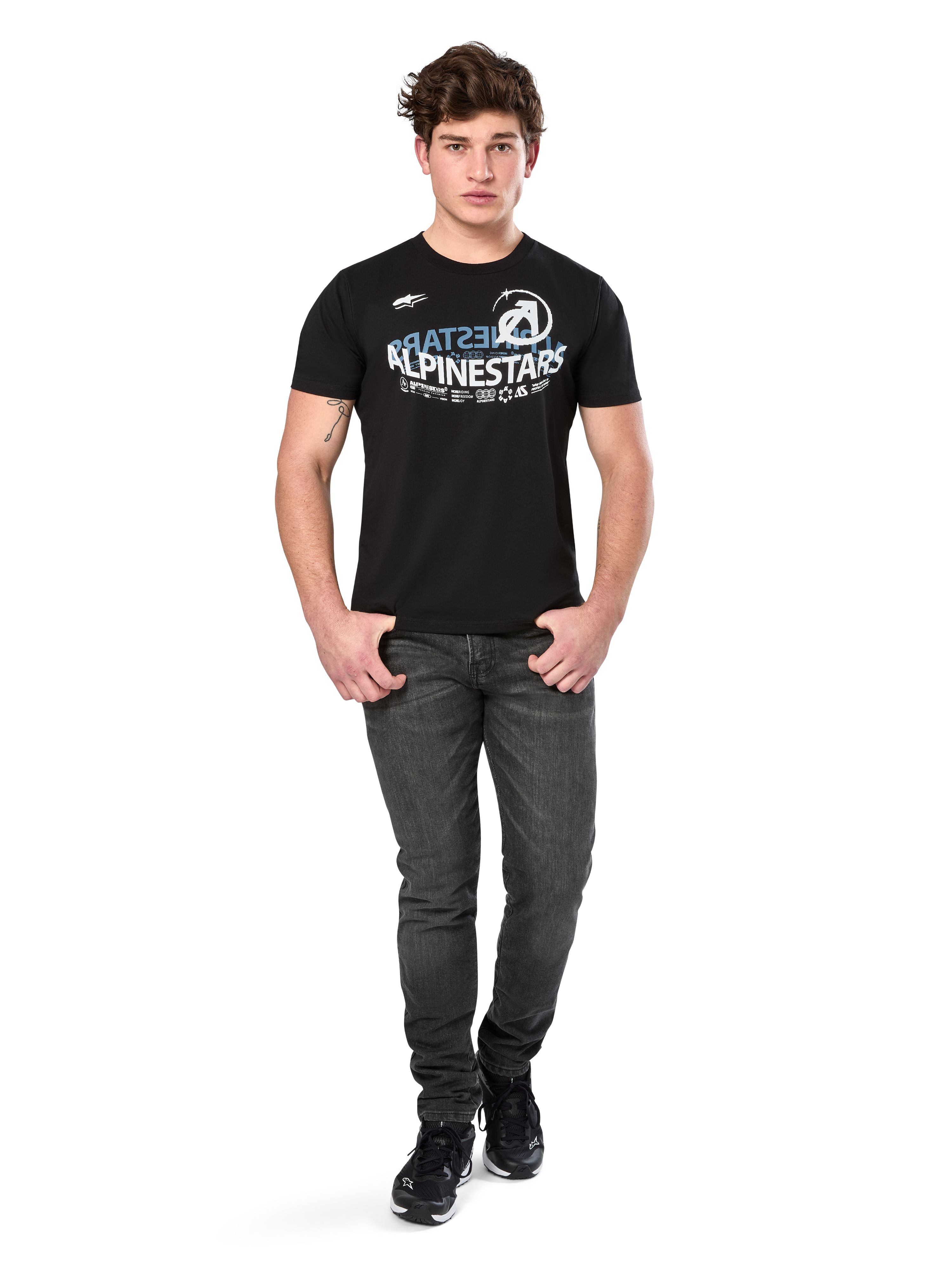 Alpinestars Semicircle CSF Tee, kortärmad t-shirt, svart, vit och ljusblå böjd grafik på bröstet, bärs av modell med mörkgrå jeans och svarta sneakers, avslappnad motorsport-streetwear