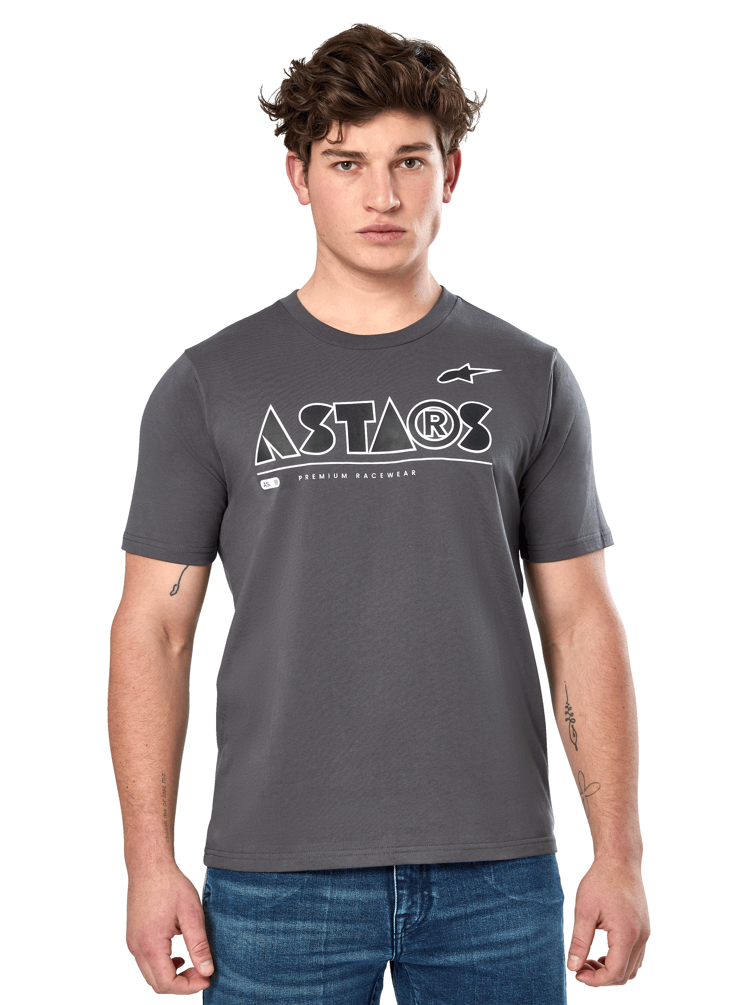 Alpinestars Cereal CSF Tee, mörkgrå kortärmad t-shirt buren av en manlig modell i blå jeans, vit geometrisk ASTARS-logotyp och texten "Premium Racewear", avslappnade motorsportinspirerade livsstilskläder