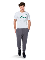 Alpinestars Geografica CSF Tee, kortärmad T-shirt, vit, grön Astars-logotyp med geografisk multi-tech-grafik, bärs med grå mjukisbyxor och svarta sneakers, avslappnad motorsport-streetwear