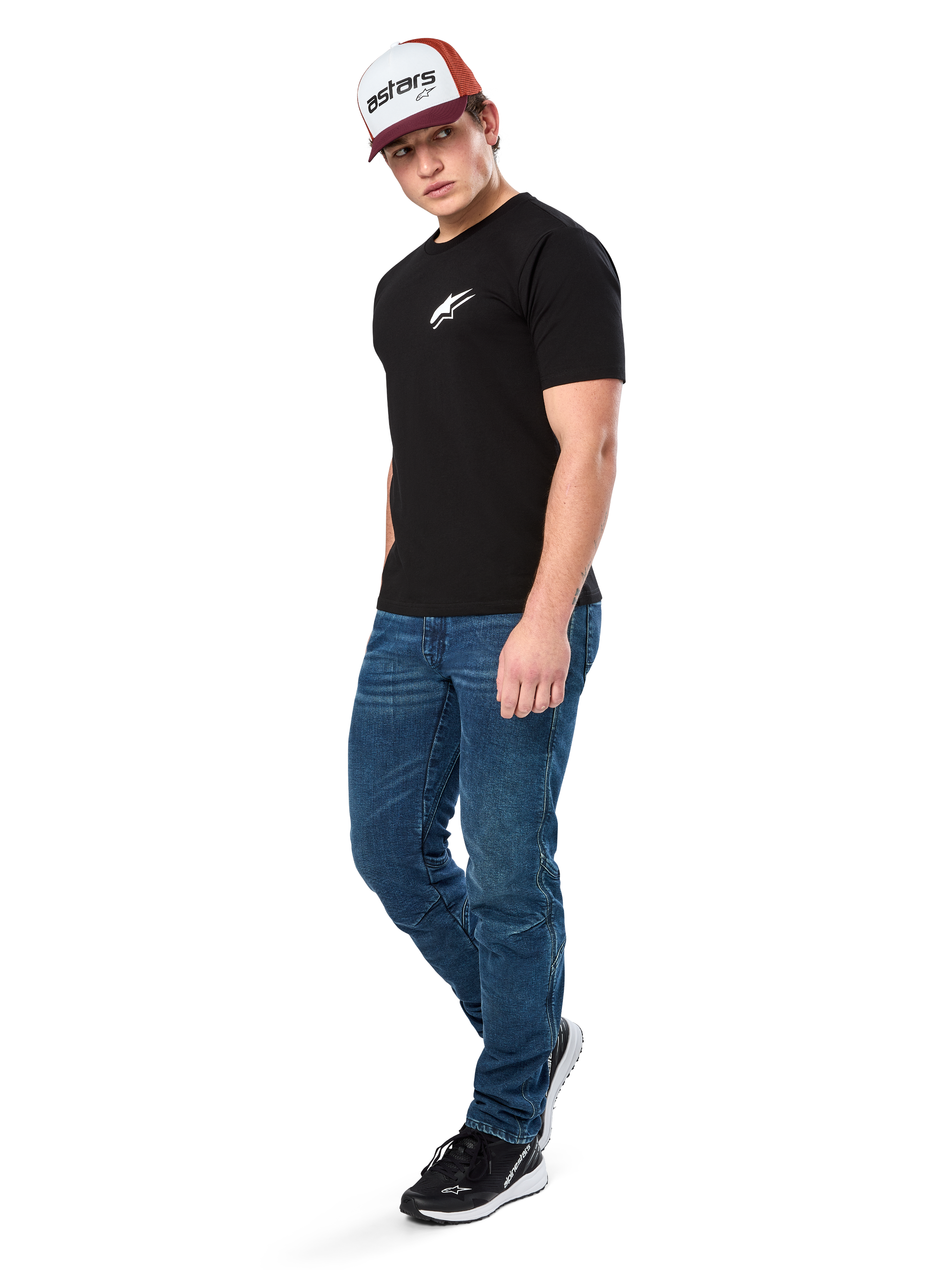 Alpinestars Formulate Csf Tee, kortärmad t-shirt, svart med vit Astars-logotyp på bröstet, bärs av en modell med blå jeans, en vinröd och vit keps och svarta sneakers, avslappnad motorsport-inspirerad streetwear