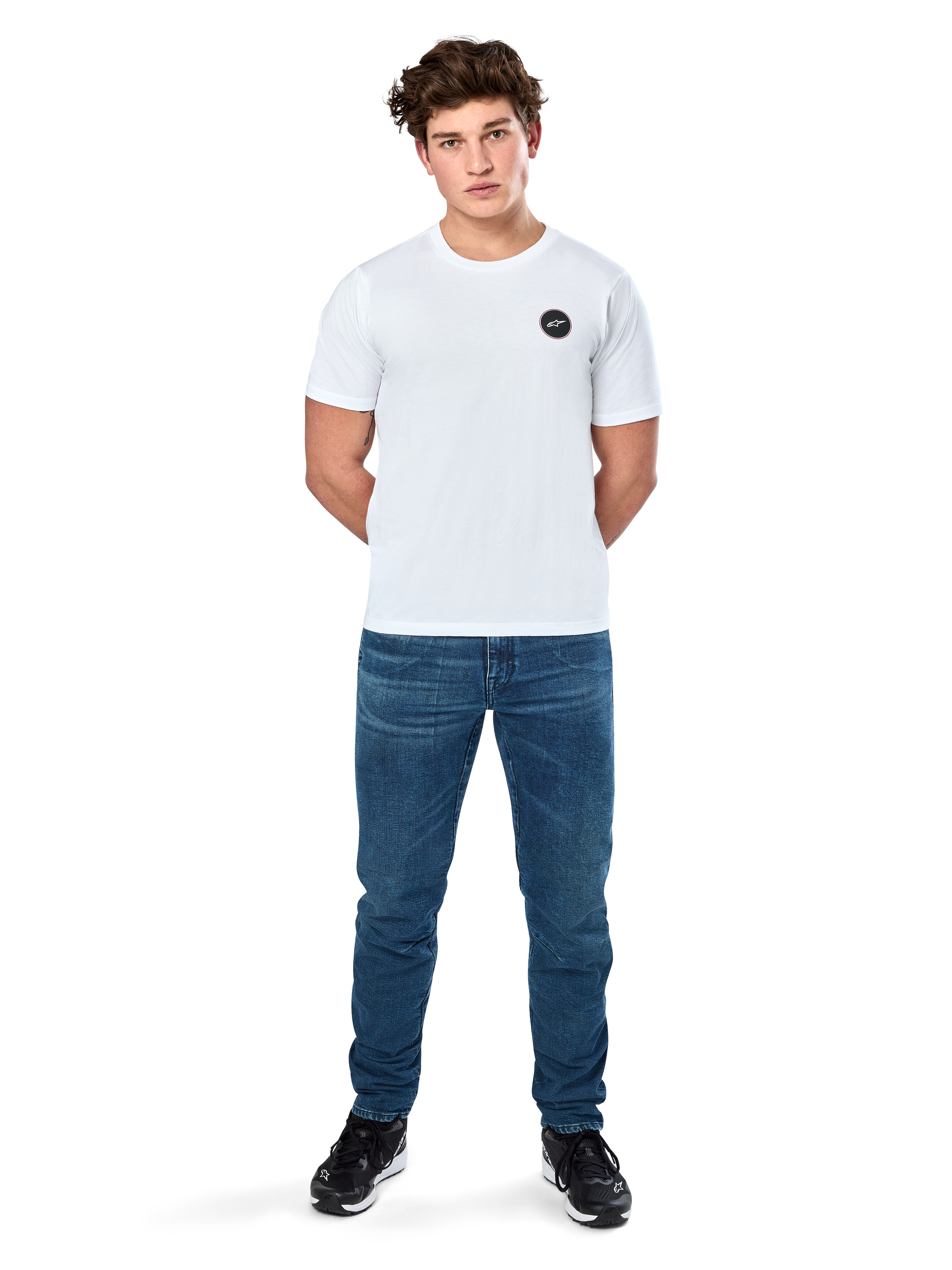 Alpinestars Dot Carbon Csf Tee, kortärmad t-shirt, vit, rund Astars-logotyp med kolfiberutseende, casual motorsport-streetwear, bärs av en manlig modell med blå jeans och svarta sneakers