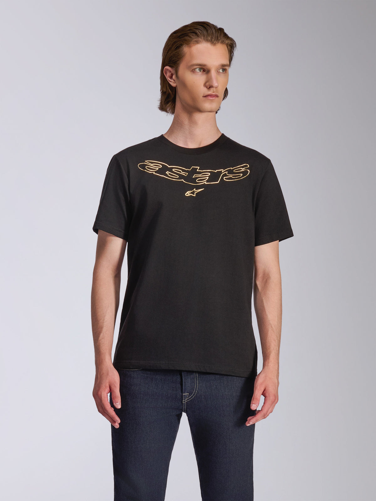 Alpinestars Luxo CSF Tee, kortärmad t-shirt, svart, guld-konturerad Astars-logotyp på bröstet, bärs med mörkblå jeans, avslappnad motorsport-streetwear