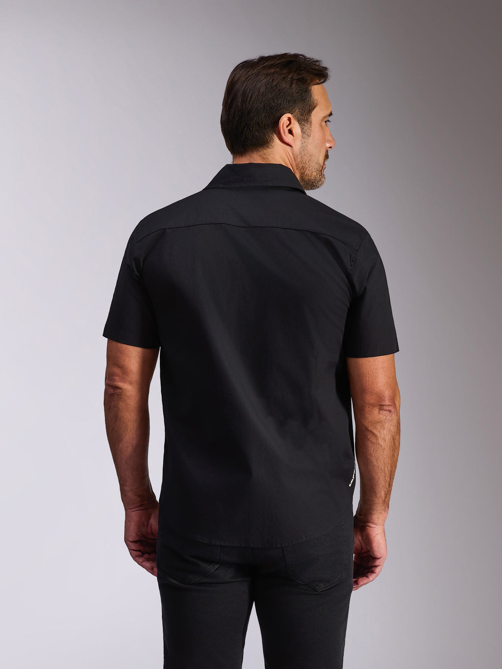 Alpinestars Strive Woven Shirt, svart kortärmad skjorta, vy bakifrån som visar ryggok och skräddarsydd passform, avslappnad motorsportinspirerad streetwear