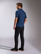 Alpinestars Impetus Sport pikétröja, marinblå kortärmad pikétröja, bak- och sidovy på modell, kombinerad med svarta byxor och svarta sneakers, avslappnade sportkläder för en motorsport-livsstil