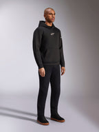 Alpinestars Insight Hoodie, svart, ledig huvtröja i fleece med vit Astars-logotyp på bröstet, känguruficka, bärs med svarta byxor och sneakers, studiobild i helfigur, motorsportinspirerad streetwear