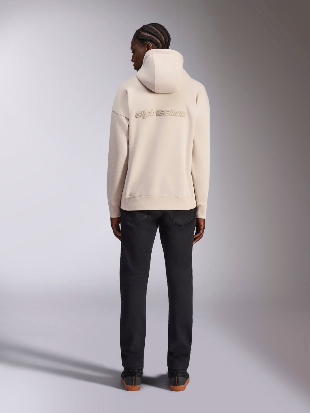 Alpinestars Emergent Oversized Hoodie, Off White, vy bakifrån med 3D-broderad Alpinestars ordlogotyp, oversized fleece-huvtröja, matchad med svarta byxor, avslappnad streetwear-design