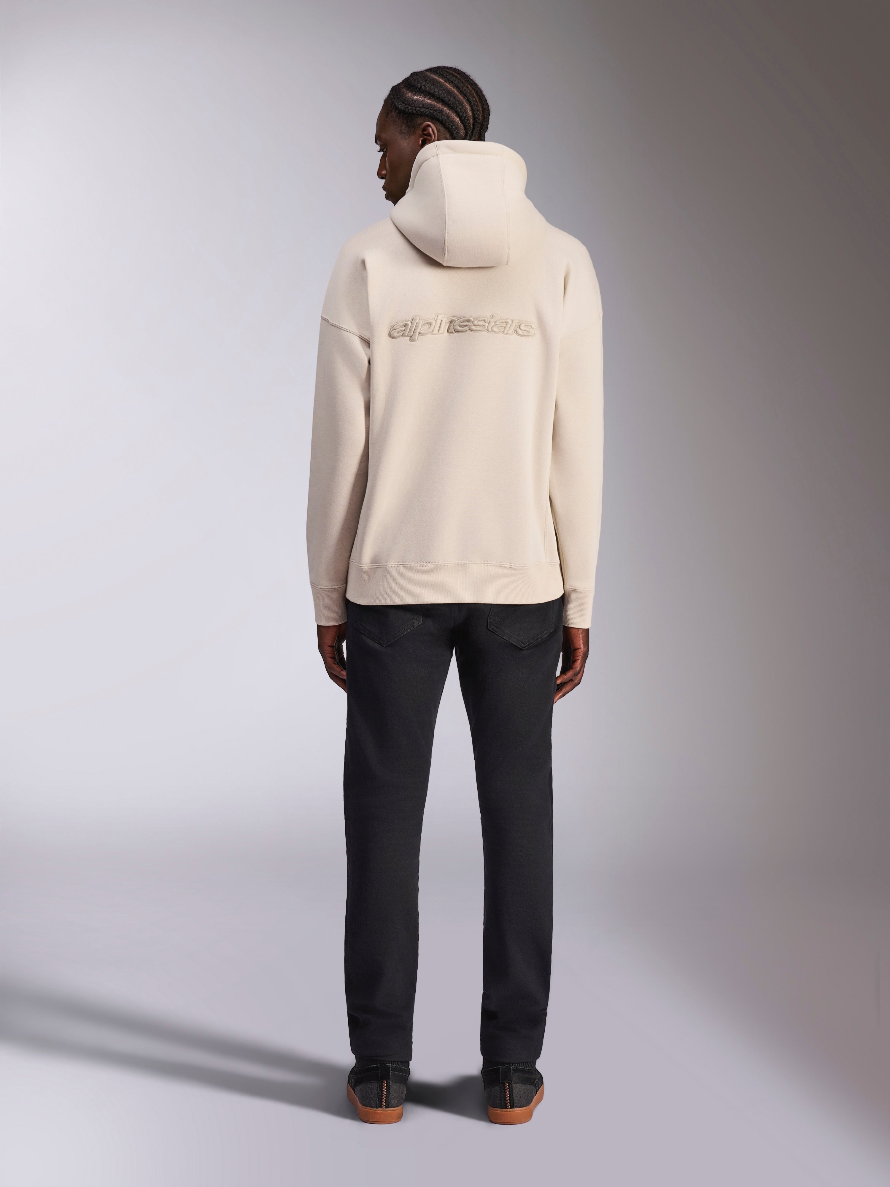 Alpinestars Emergent Oversized Hoodie, Off White, vy bakifrån med 3D-broderad Alpinestars ordlogotyp, oversized fleece-huvtröja, matchad med svarta byxor, avslappnad streetwear-design