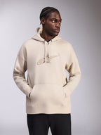 Alpinestars Emergent Oversized Hoodie, sandfärgad, pullover med oversized passform och ton-i-ton 3D-broderad Astars-logotyp på bröstet, känguruficka, huva med dragsnöre, casual streetwear som bärs av modell med svarta byxor.