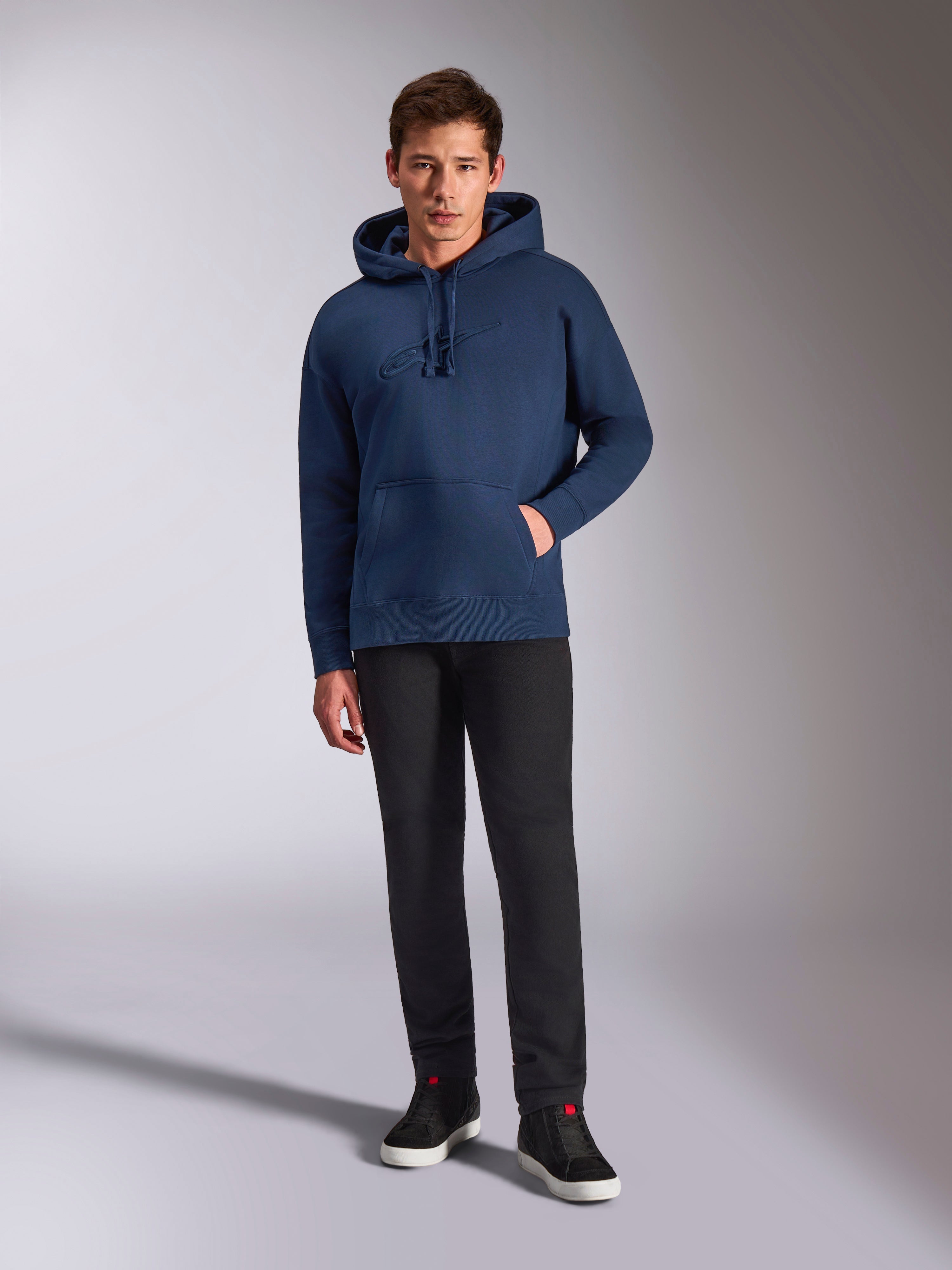 Alpinestars Emergent Oversized Hoodie, Navy Blue pullover fleece hoodie, tonal 3D logo embroidery on front, worn by model with black pants and sneakers, casual streetwear style.