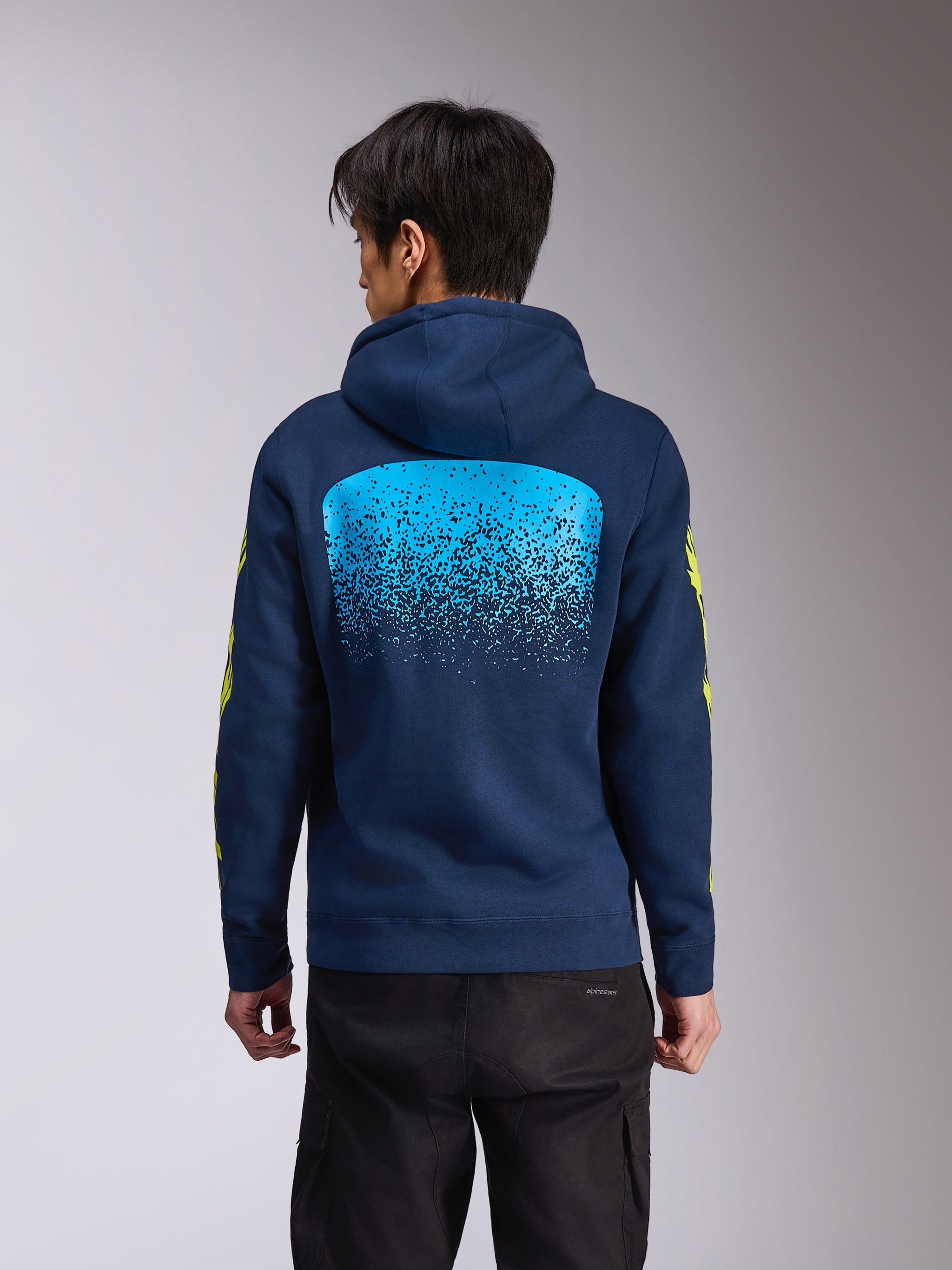 Alpinestars Obsessed Hoodie, marinblå huvtröja i fleece, vy bakifrån med en stor ljusblå MX-graderingsgrafik, gul Alpinestars-ordlogotyp på ärmarna, avslappnad motorsportinspirerad streetwear
