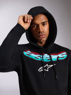 Alpinestars Ellipsoid Hoodie, svart huvtröja i fleece, med stiliserad Astars-text i turkos och röd färggradient och vit logotyp på bröstet, bärs av modell med huvan uppfälld, avslappnad motorsportinspirerad streetwear
