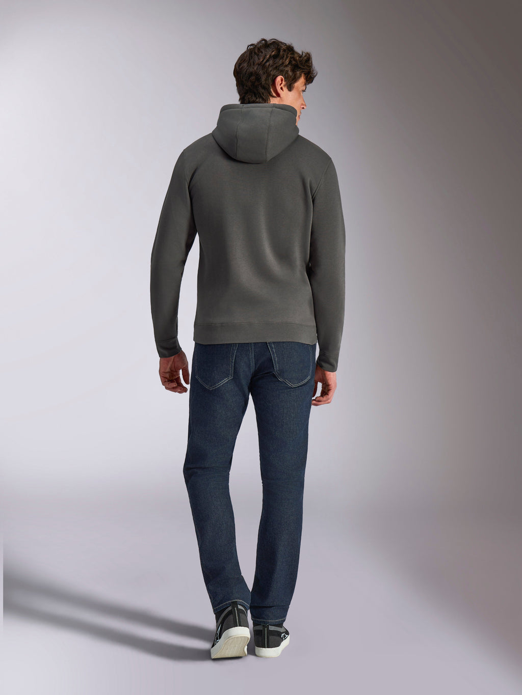 Alpinestars Ellipsoid Hoodie, gunmetal-grå huvtröja, sedd bakifrån, bärs av modell med mörka denimjeans och svarta sneakers, vardaglig motorsport-inspirerad streetwear