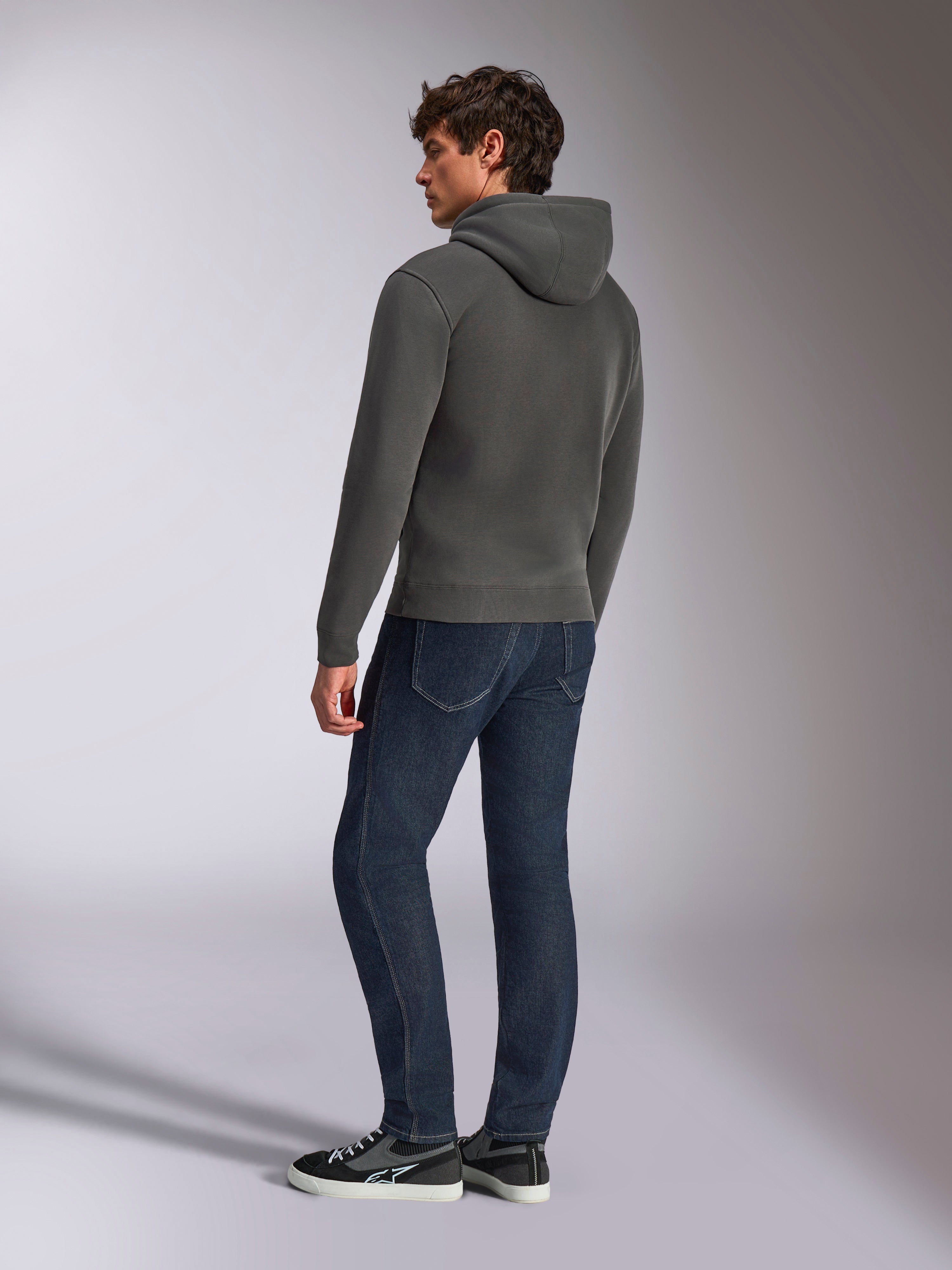 Alpinestars Ellipsoid Hoodie, casual sportkläder, gunmetal-grå, ryggvy på manlig modell, huva med dragsnöre, långa ärmar, ribbade muddar och fåll, matchad med mörka jeans och sneakers