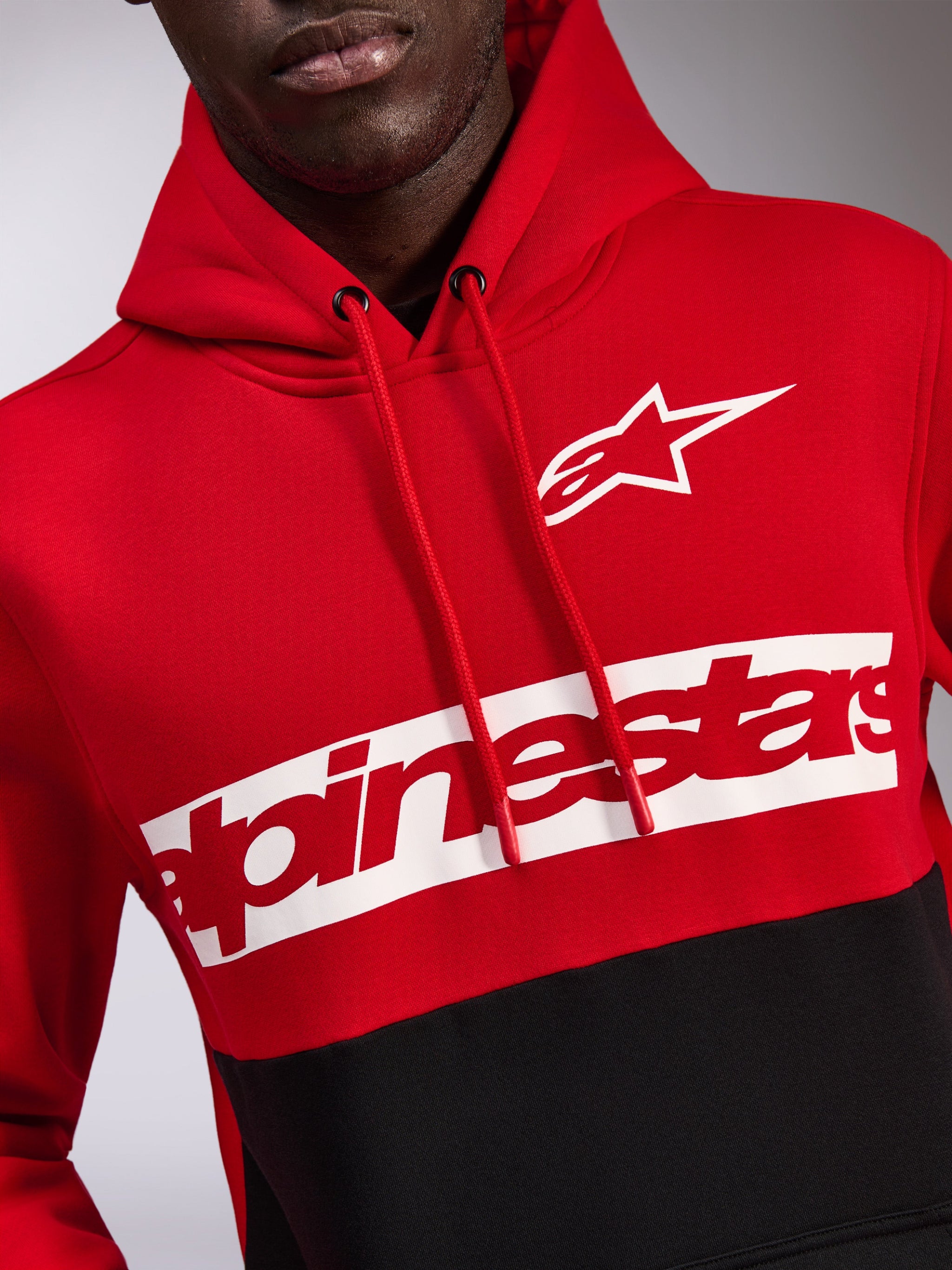 Alpinestars Parallel Hoodie, Red and Black color-blocked fleece, featuring a white Astars logo and red Alpinestars wordmark on a white chest band, drawstring hood, casual motorsport-inspired streetwear