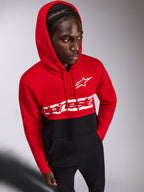 Alpinestars Parallel Hoodie, vardaglig huvtröja i fleece, röd och svart färgblockerad design, vit Alpinestars ordlogotyp och Astars-logotyp på bröstet, bärs av en man med huvan uppe och svarta byxor, motorsport-inspirerat streetwear